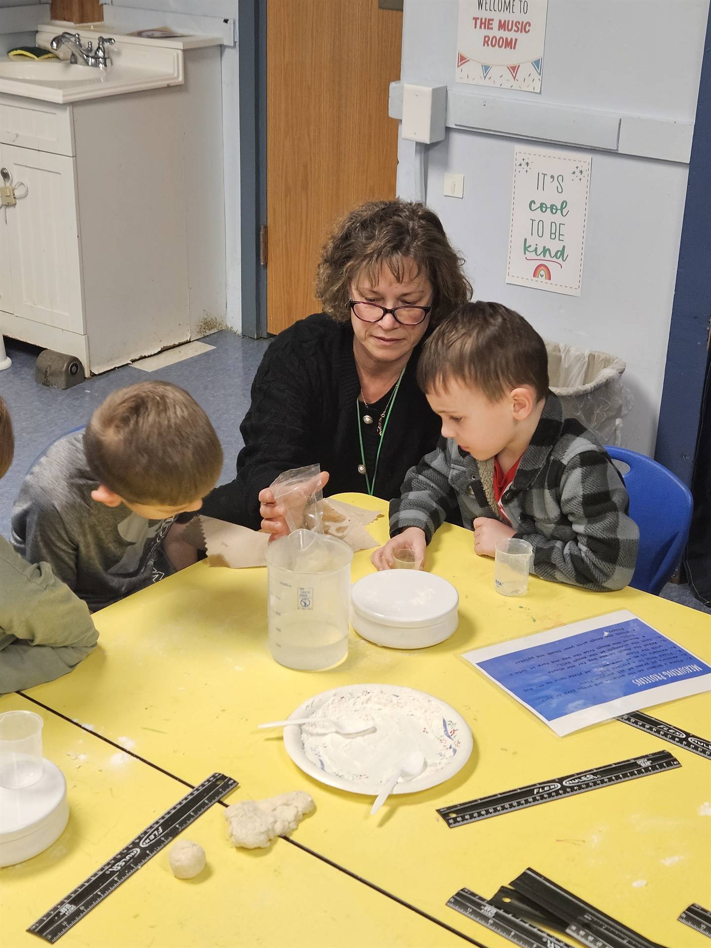 an adult works with student mixing flour and water