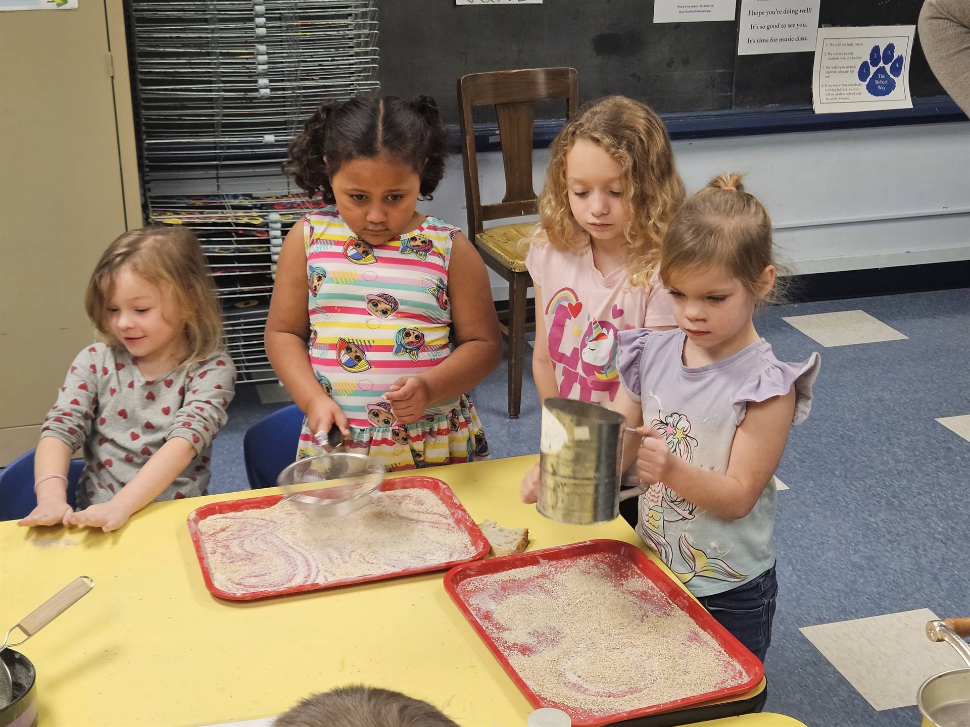 students sifting flour onto a tray 