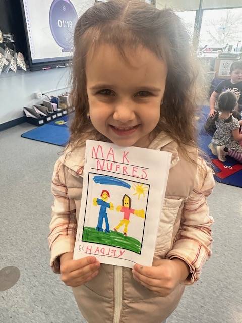 a girl holds up a book title she wrote