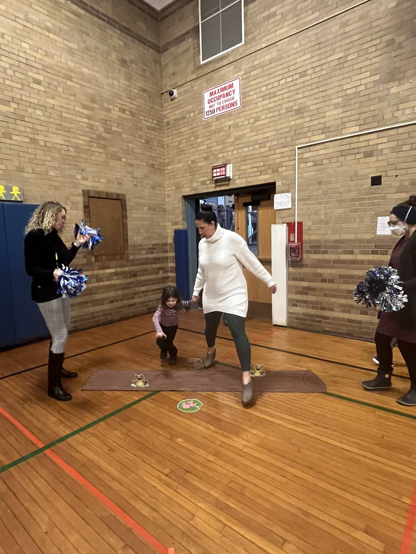 student and adult between 2 adults leaping over a paper log.