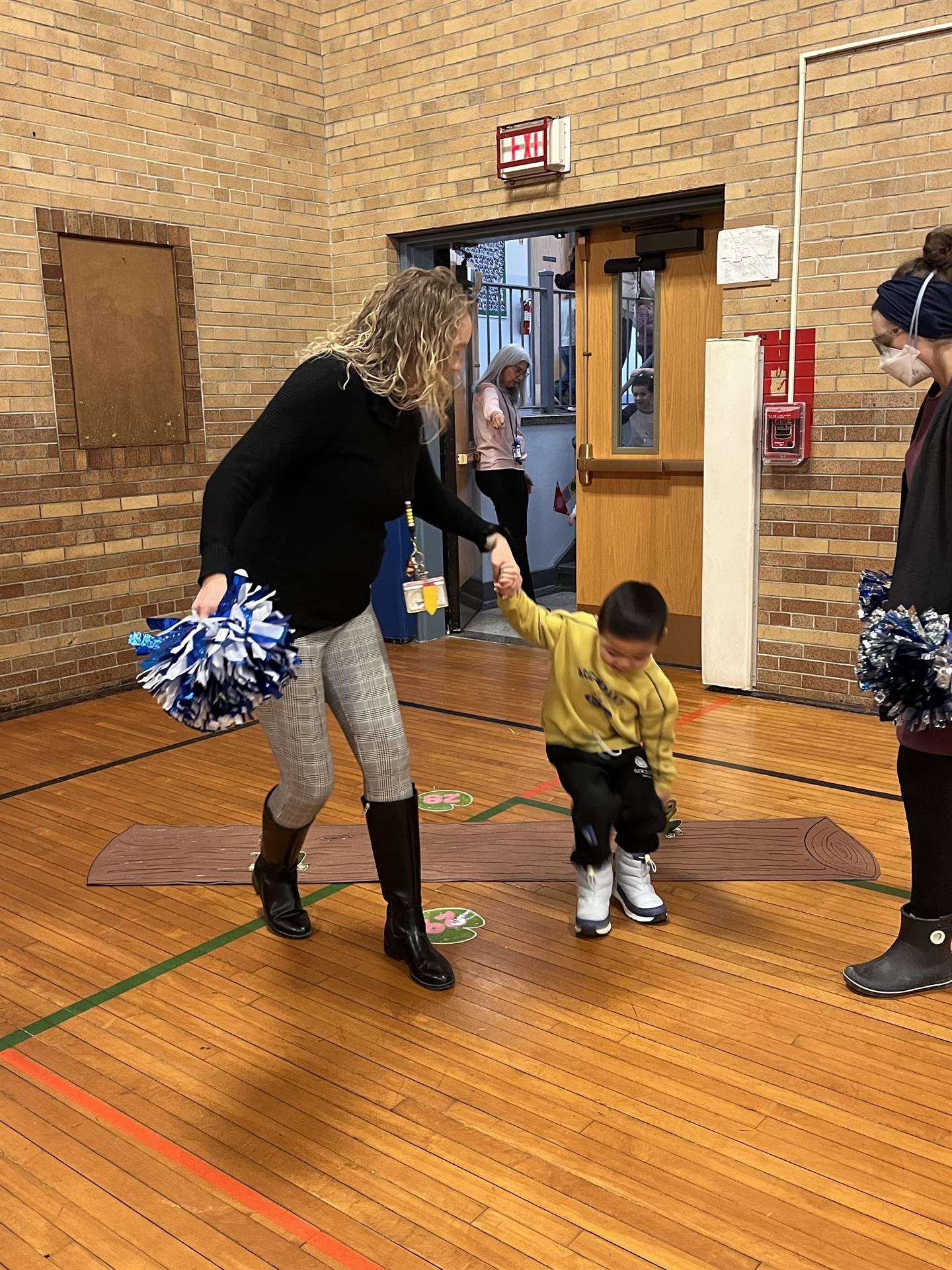 student between 2 adults leaping over a paper log.