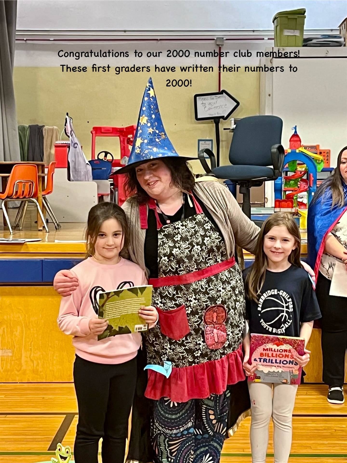 adult dressed as a wizard standing between 2 students