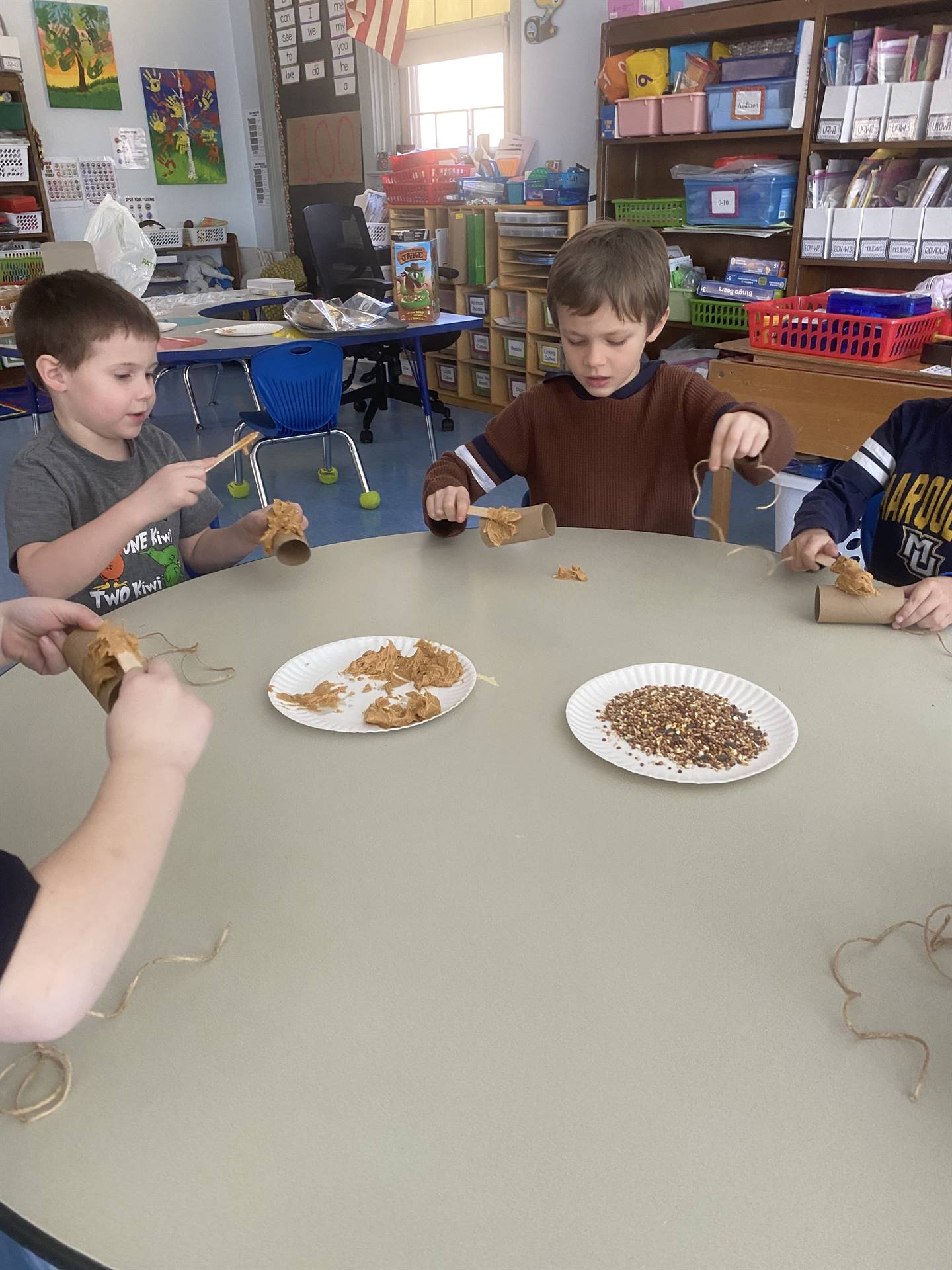 students smother peanut butter on tubes and roll in bird seed. 