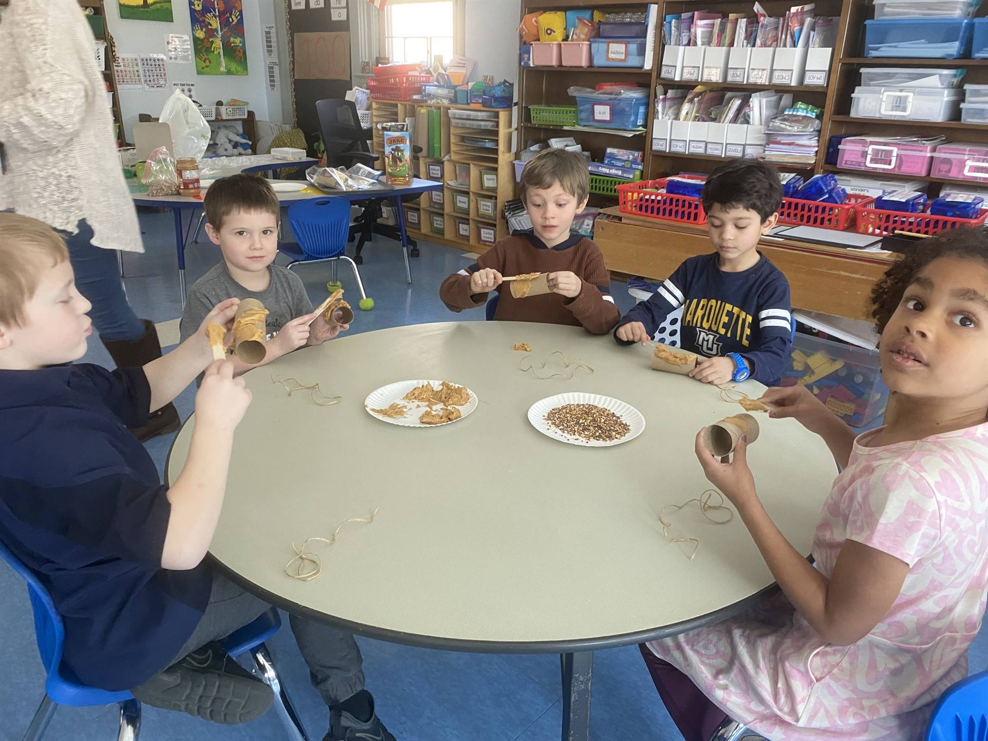 students smother peanut butter on tubes and roll in bird seed. 