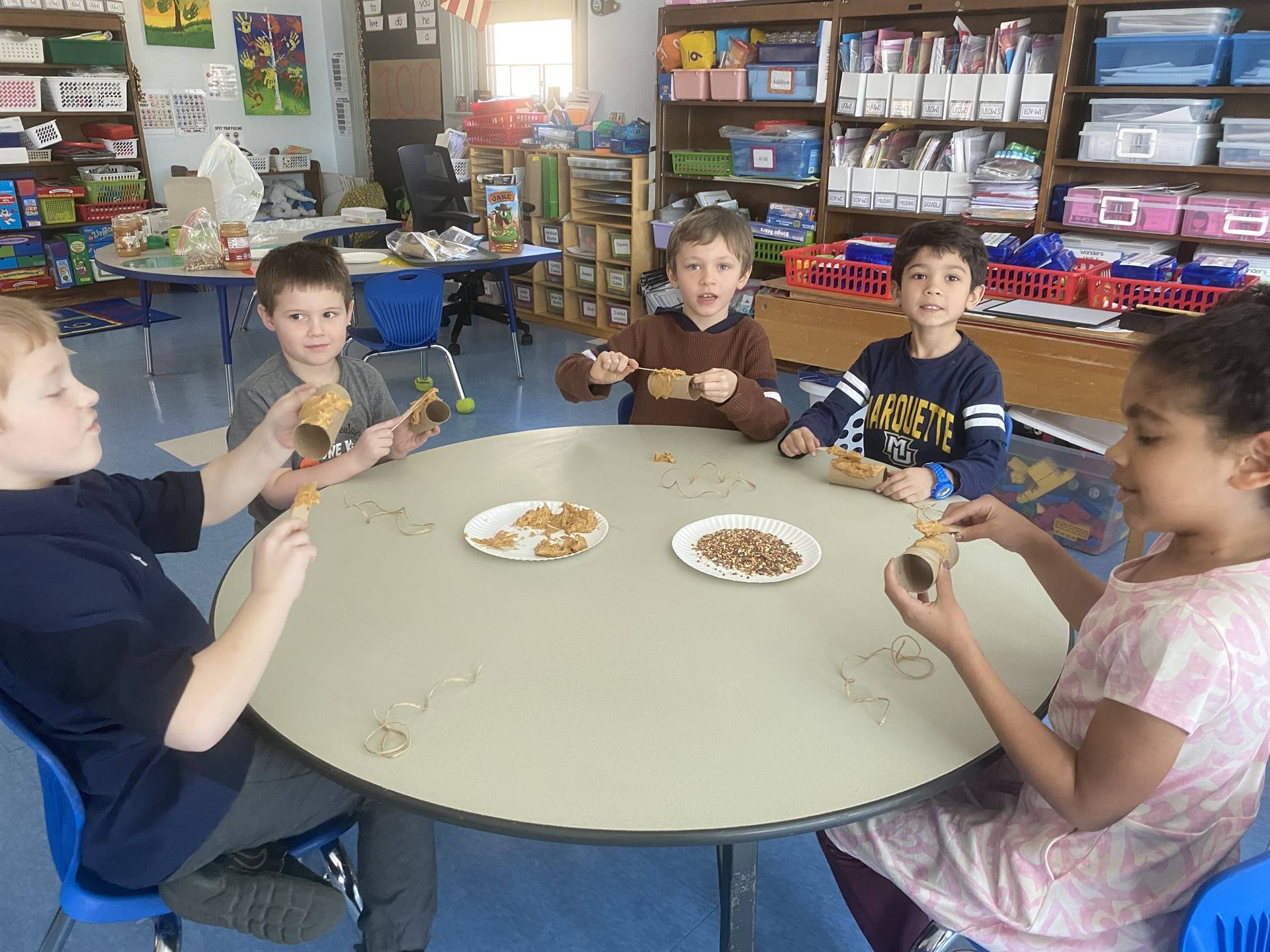 students smother peanut butter on tubes and roll in bird seed. 