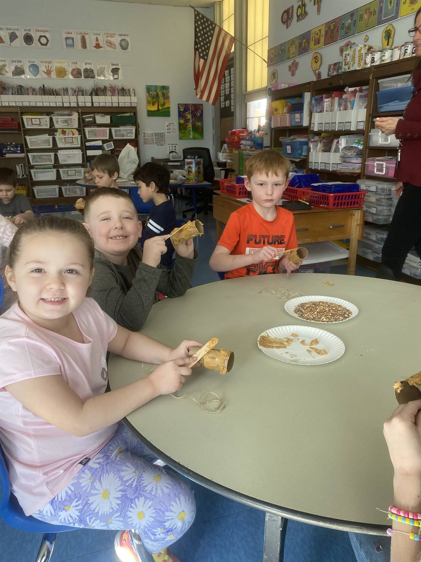 students smother peanut butter on tubes and roll in bird seed. 