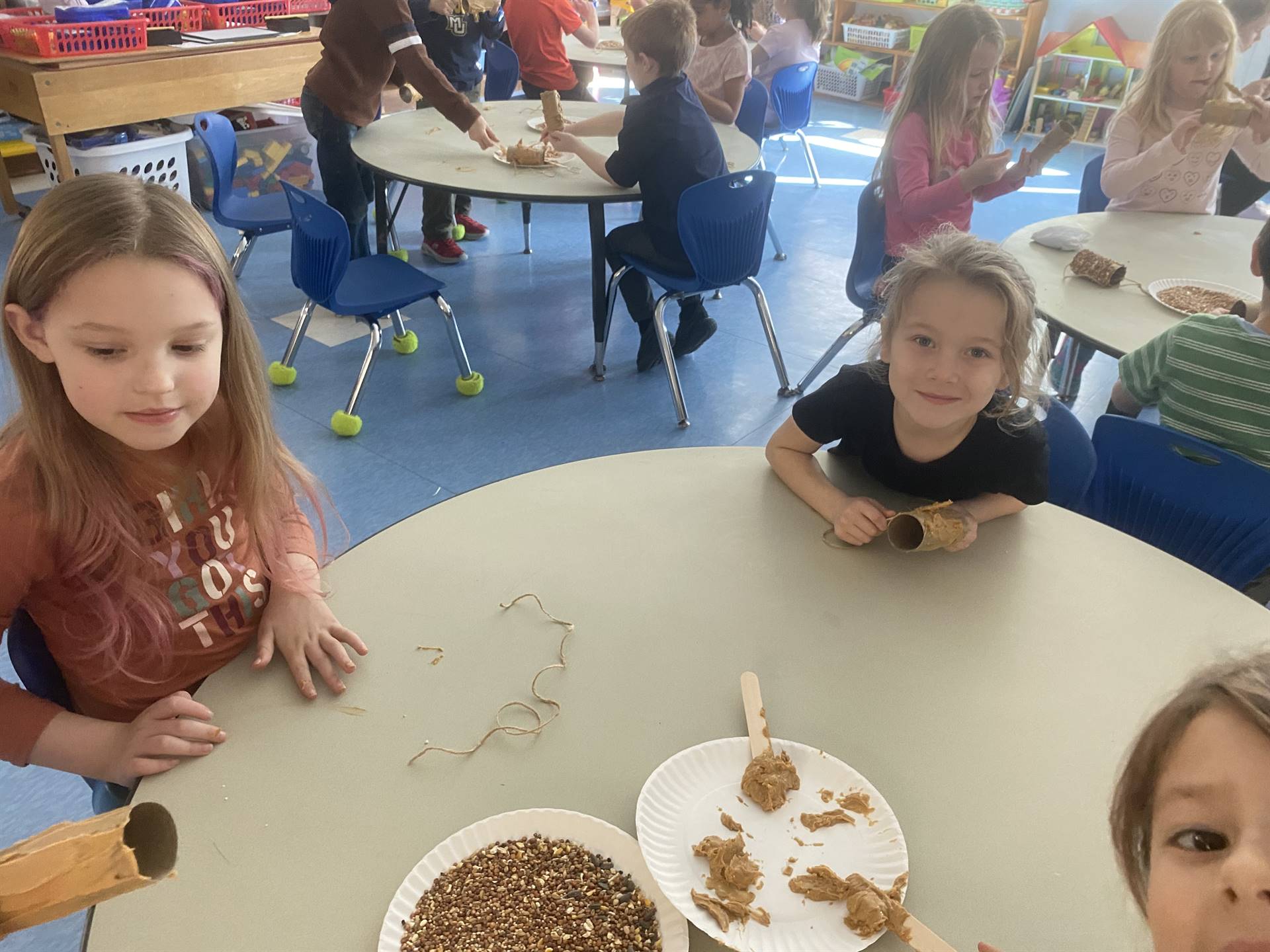 students smother peanut butter on tubes and roll in bird seed. 