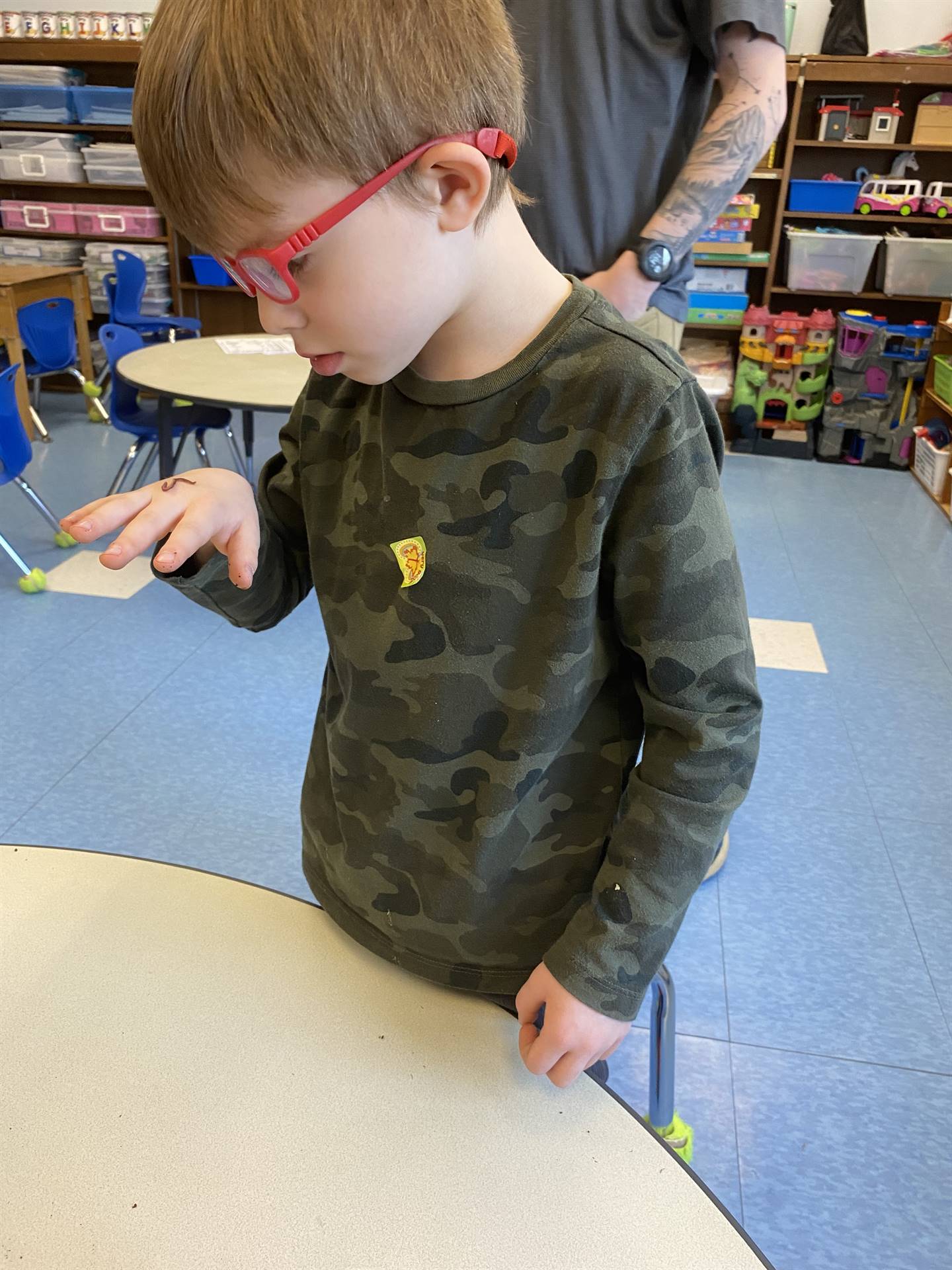 a student watches as a worm crawls on his hand.