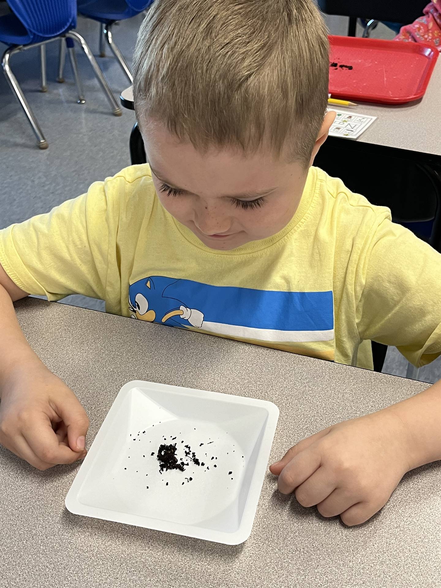 a student watches as a worm crawls on his plate
