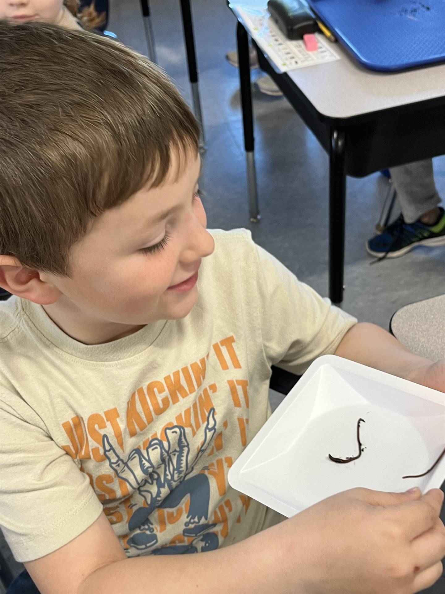 a student watches as a worm crawls on his plate