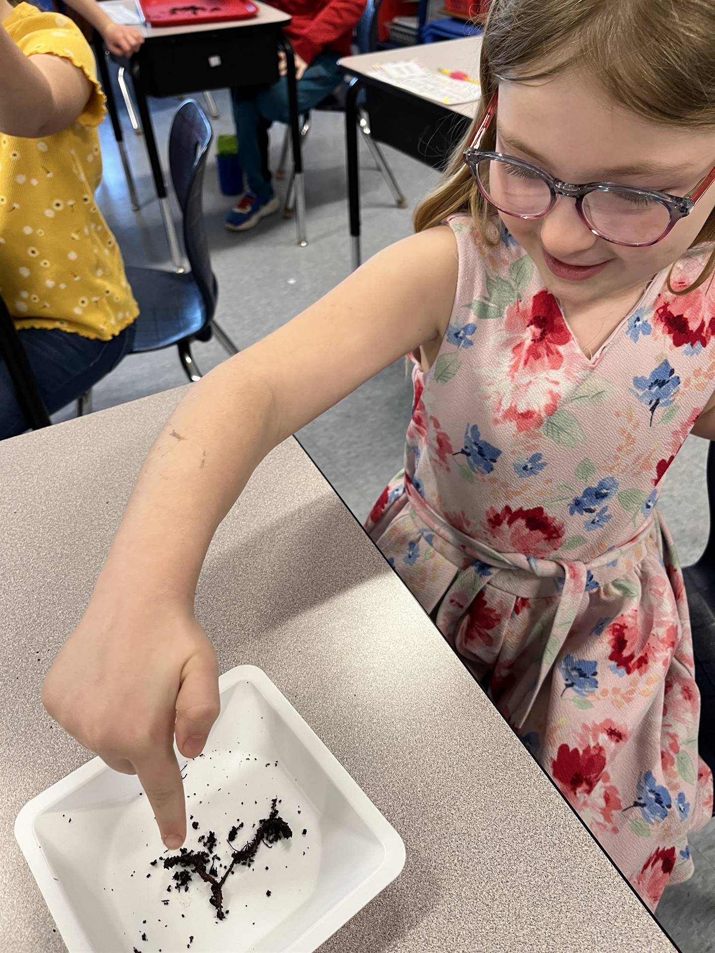 a student watches as a worm crawls on her plate