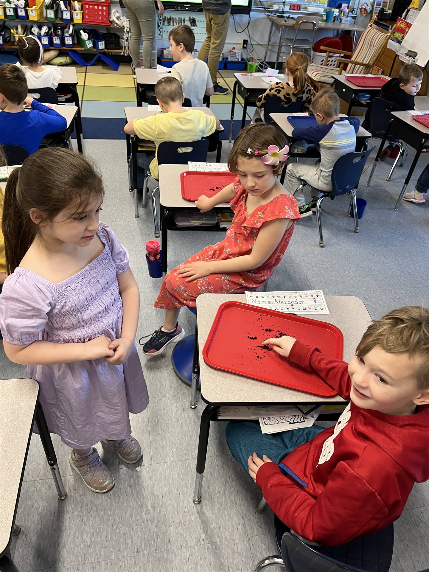 3 students point to the worms crawling on a tray