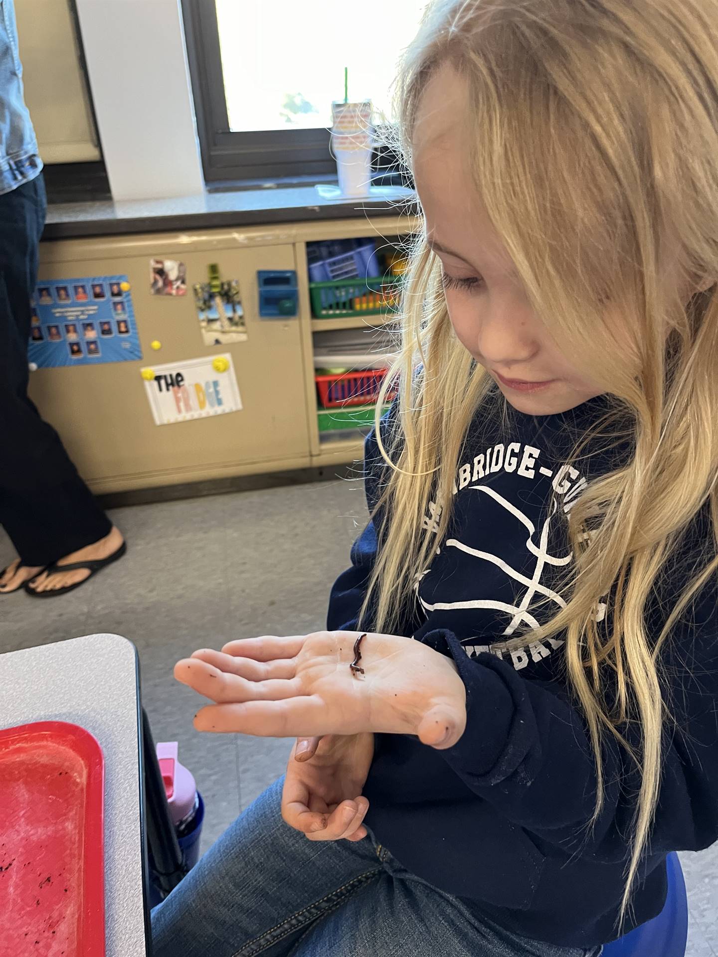 a student observes worms crawling on her hand