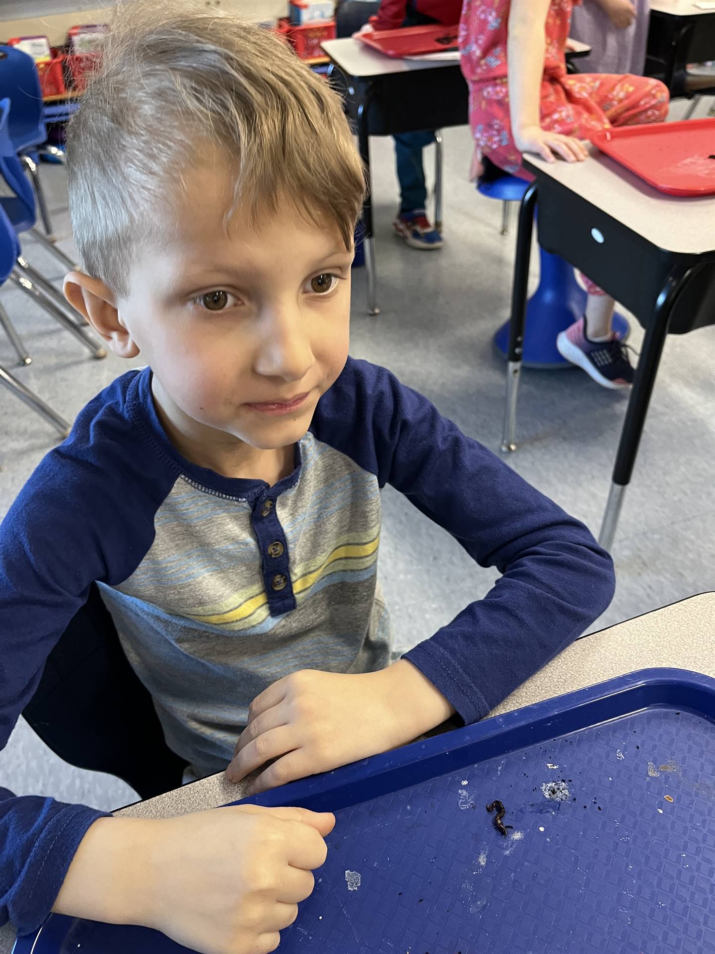 a student makes a face as worms crawl on a tray