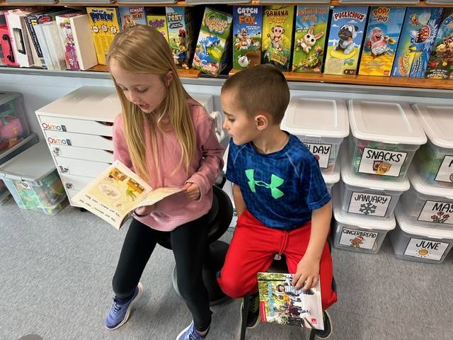 a first grader reads to a kindergarten buddy