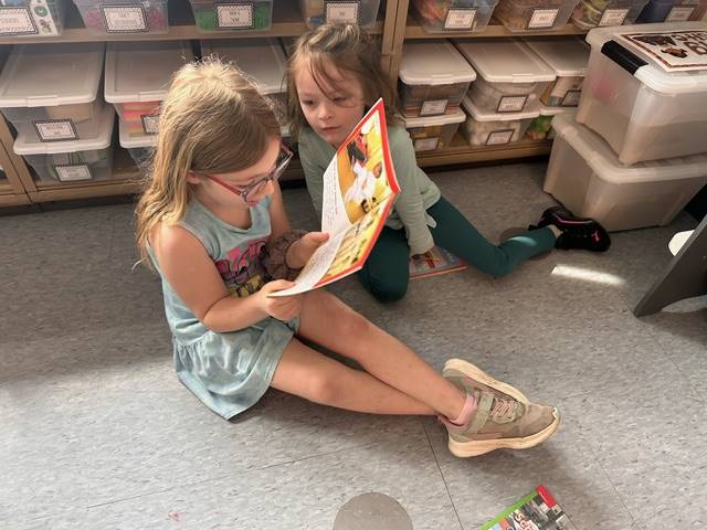 a first grader reads to a kindergarten buddy