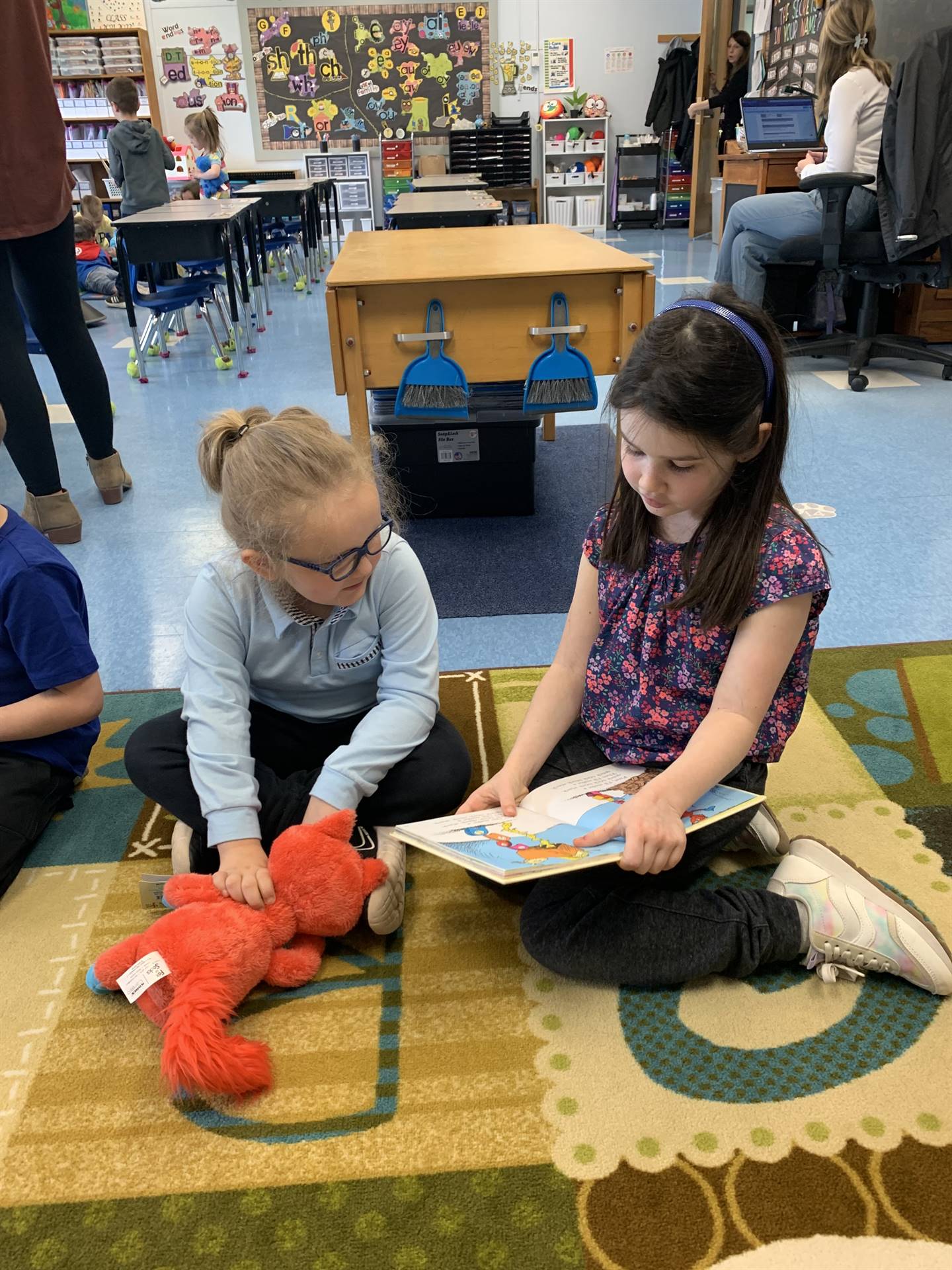 students on floor reading books with their stuffs