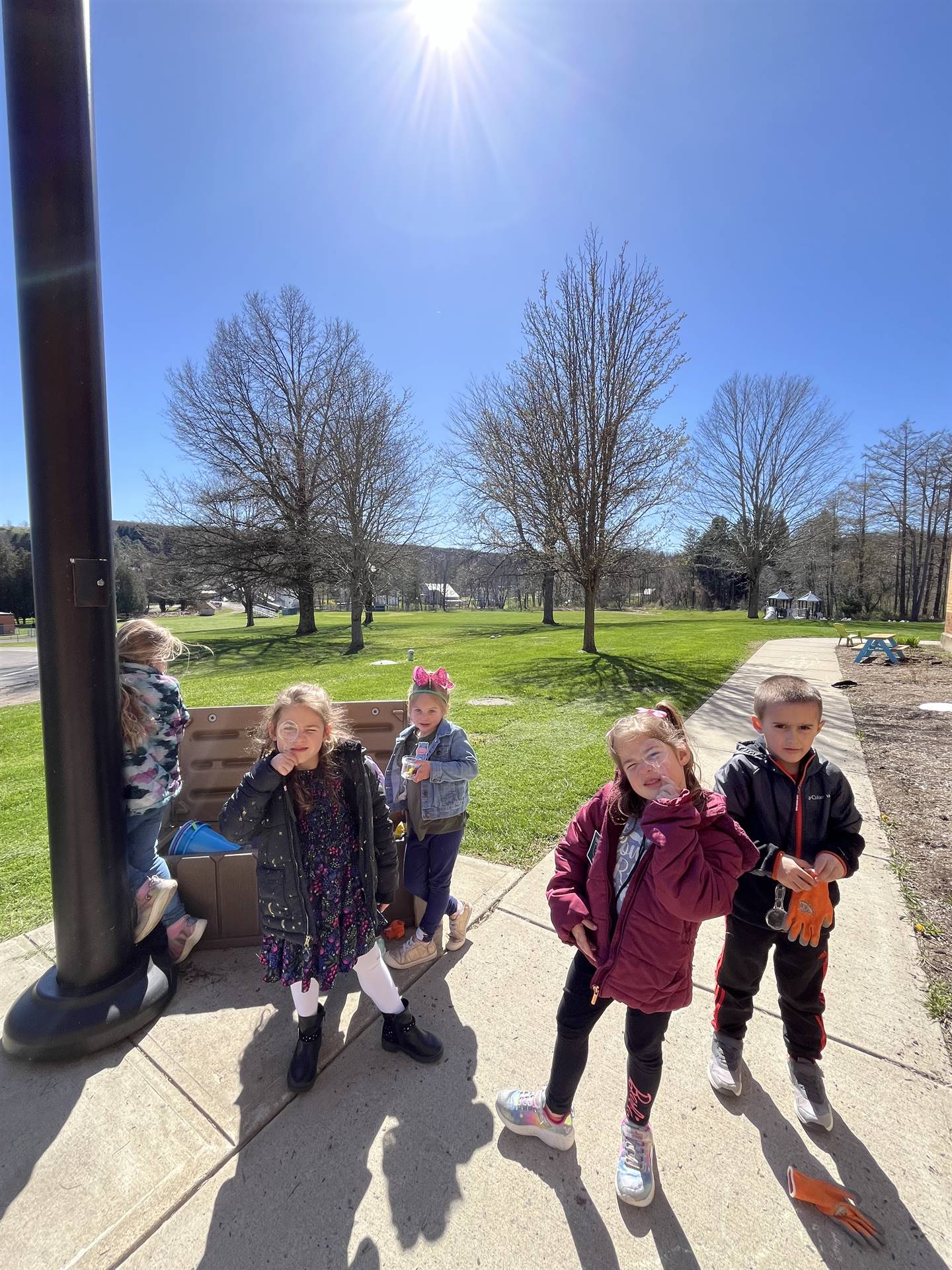 students using magnifying glasses and gloves outside.