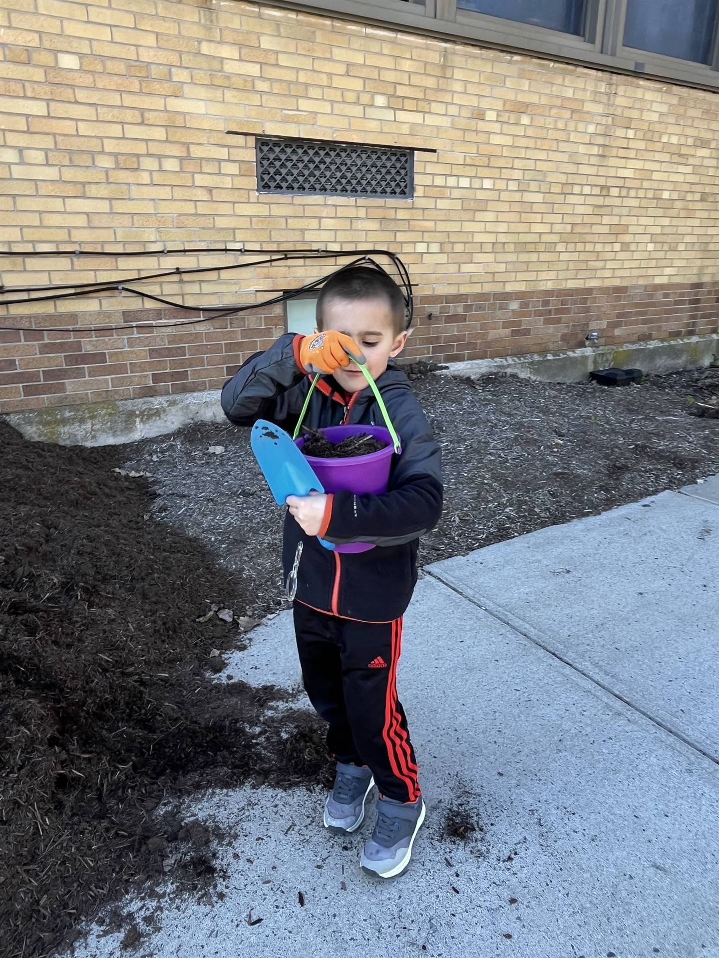 a student holds up a pail of mulch