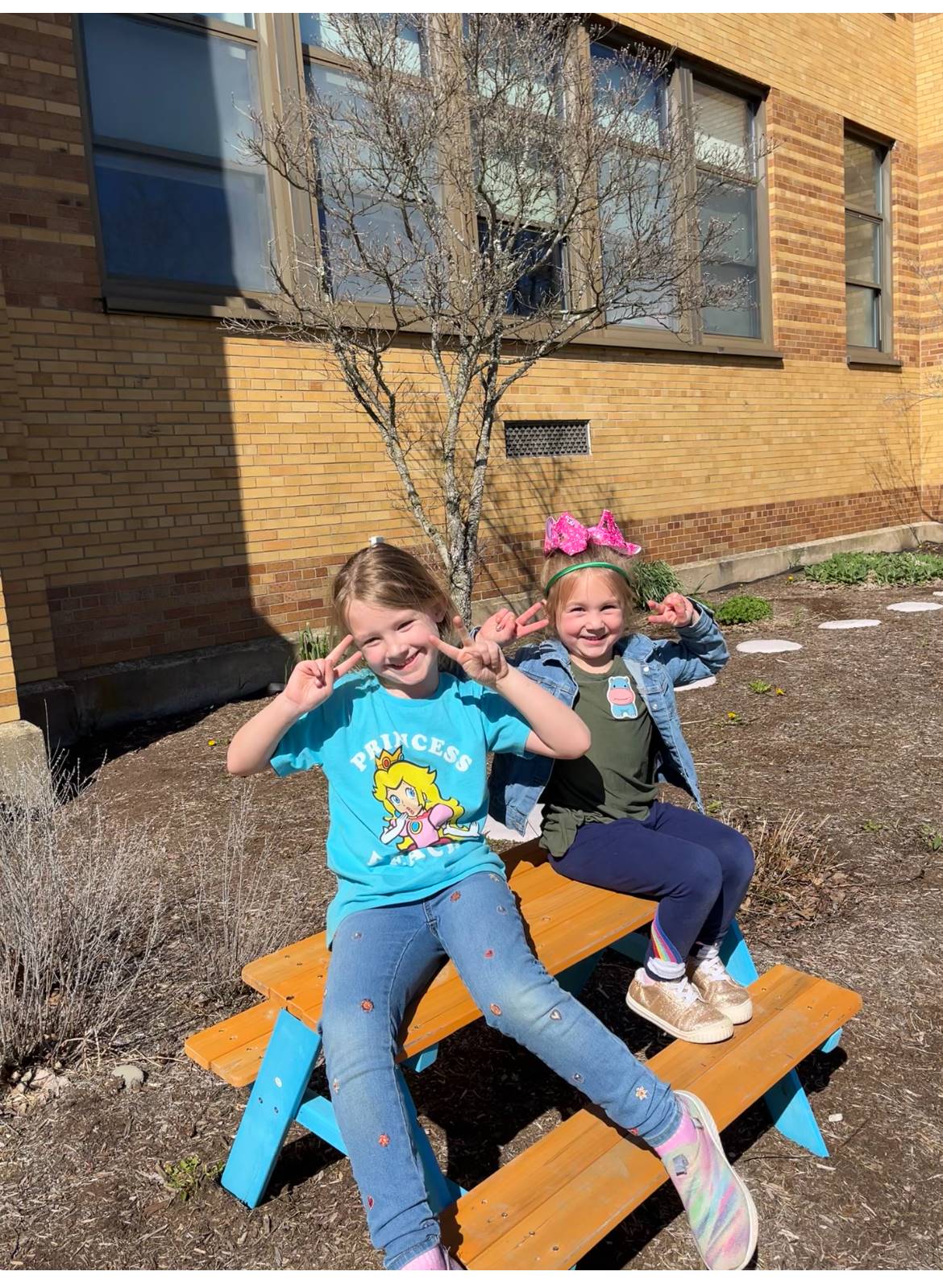 2 students sitting on picnic table outdoors.