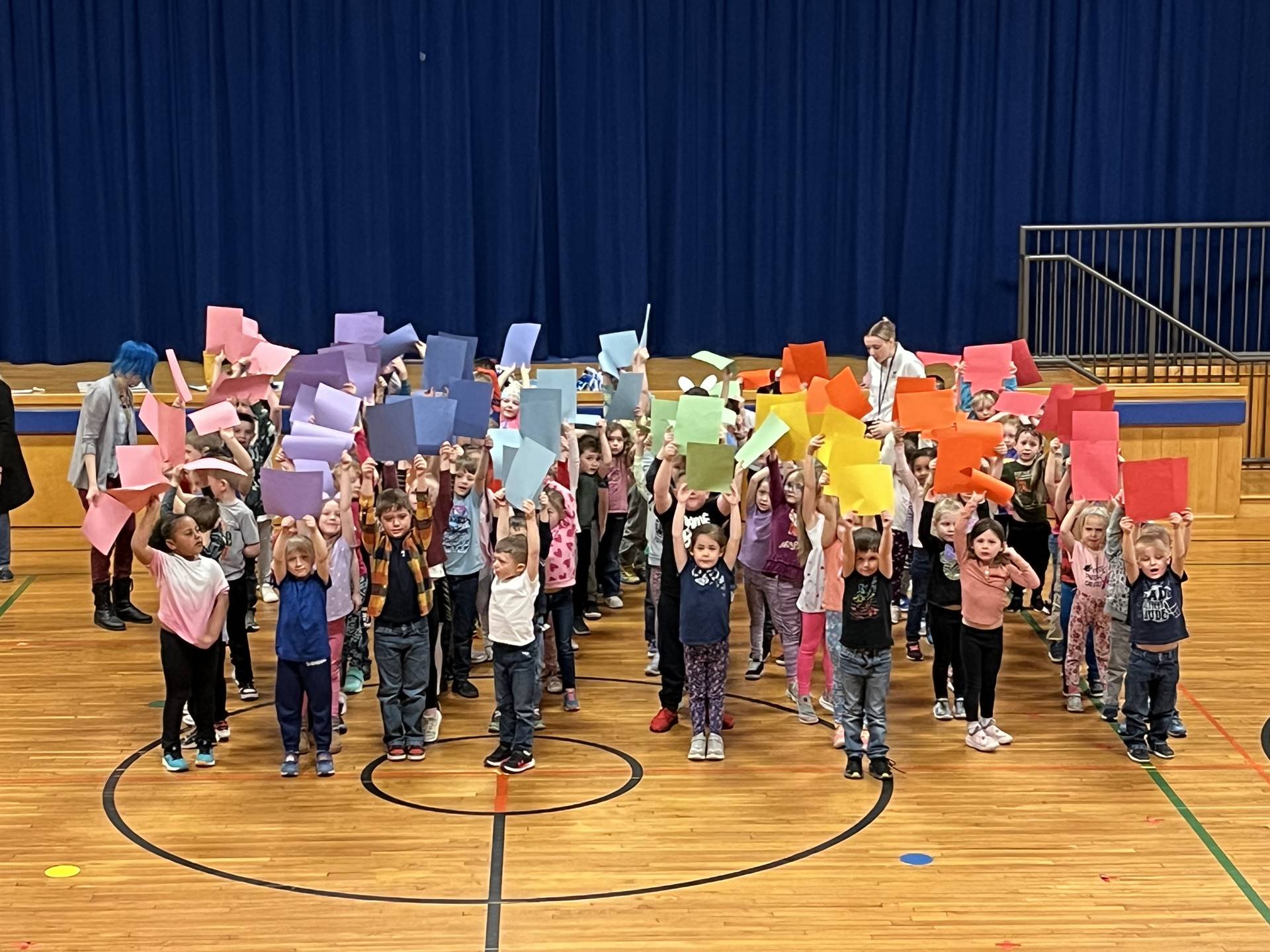 Guilford Elementary students hold up different colored papers to make a school wide rainbow!