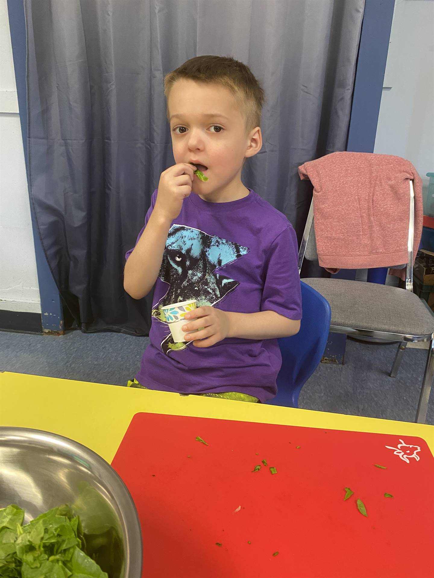 a student eating cooked swiss chard greens.