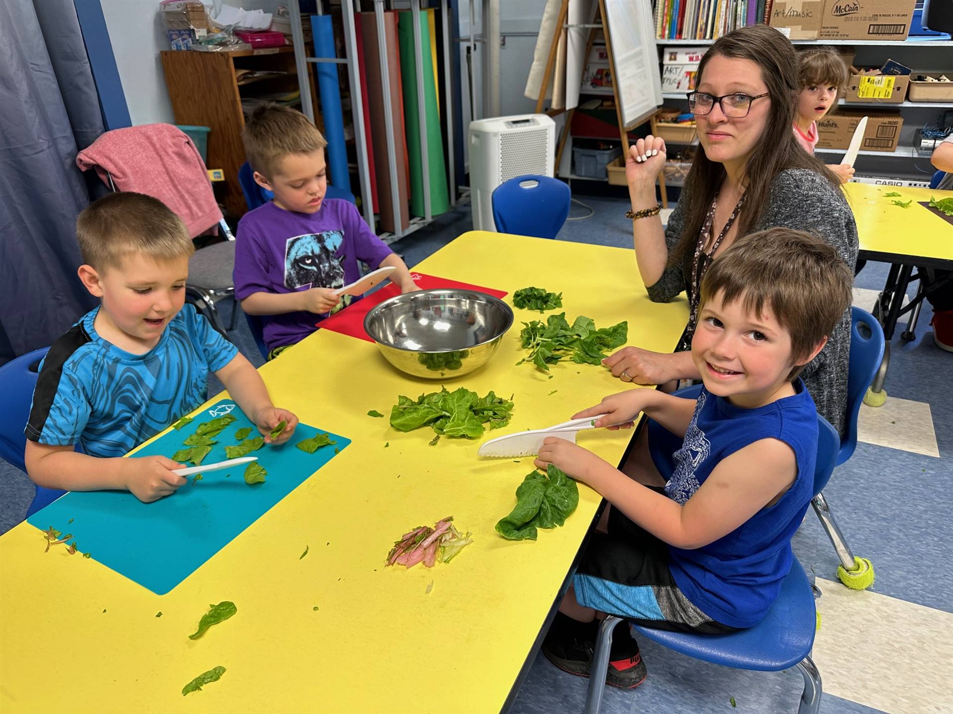 students ripping up swiss chard greens and cutting stems into a bowl.