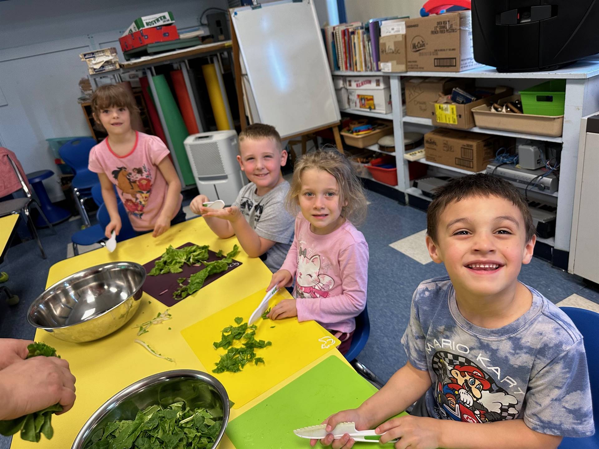 2 students ripping up swiss chard greens and cutting stems into a bowl.