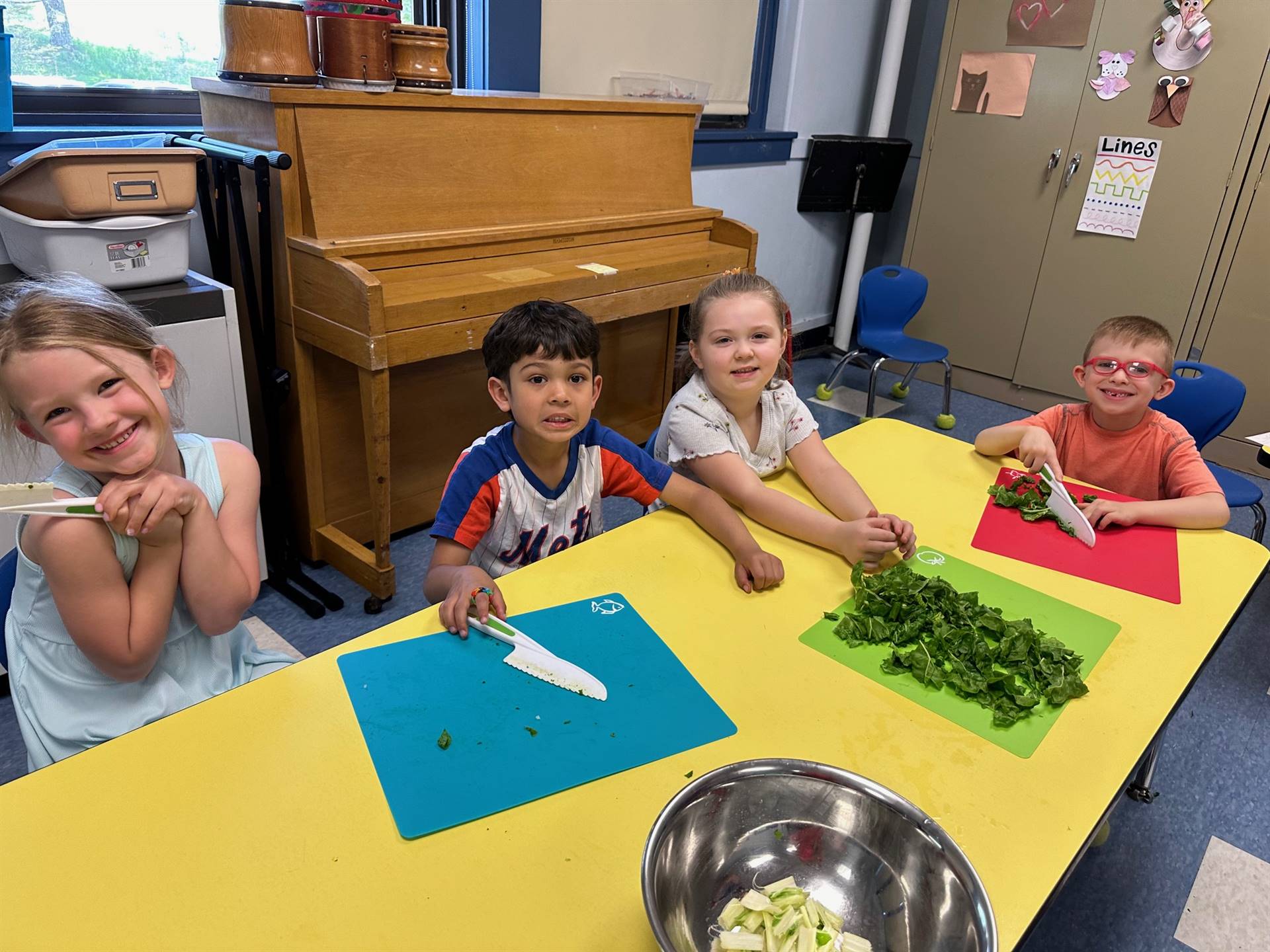 2 students ripping up swiss chard greens and cutting stems into a bowl.