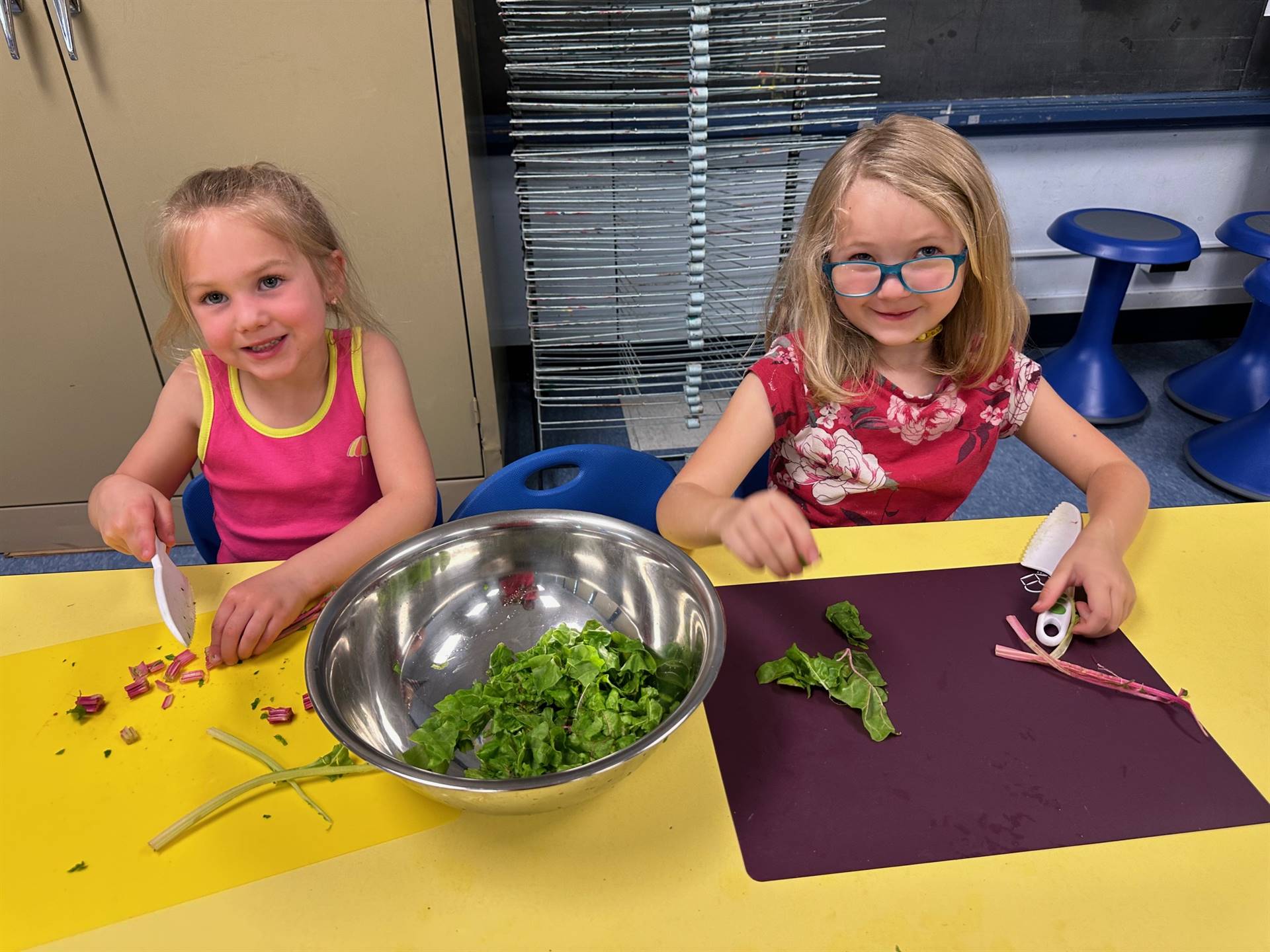 2 students ripping up swiss chard greens into a bowl.