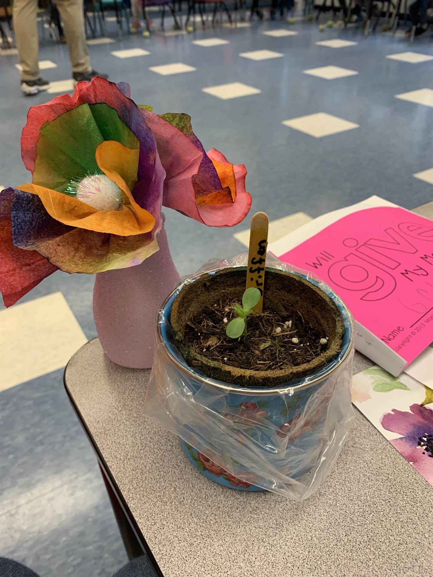 a pretty paper flower next to a plant.