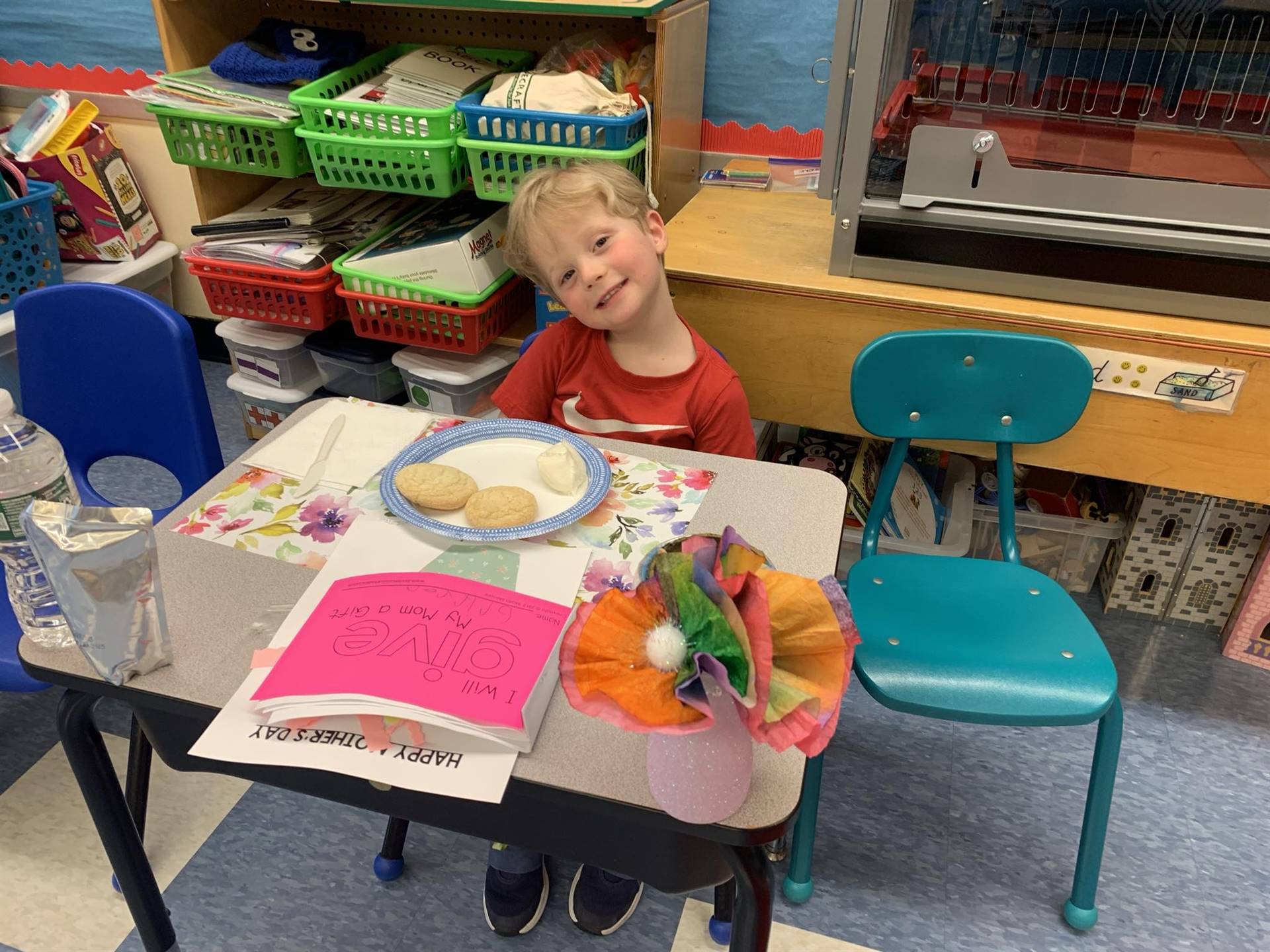 a student sits at desk with cookies and paper flowers.