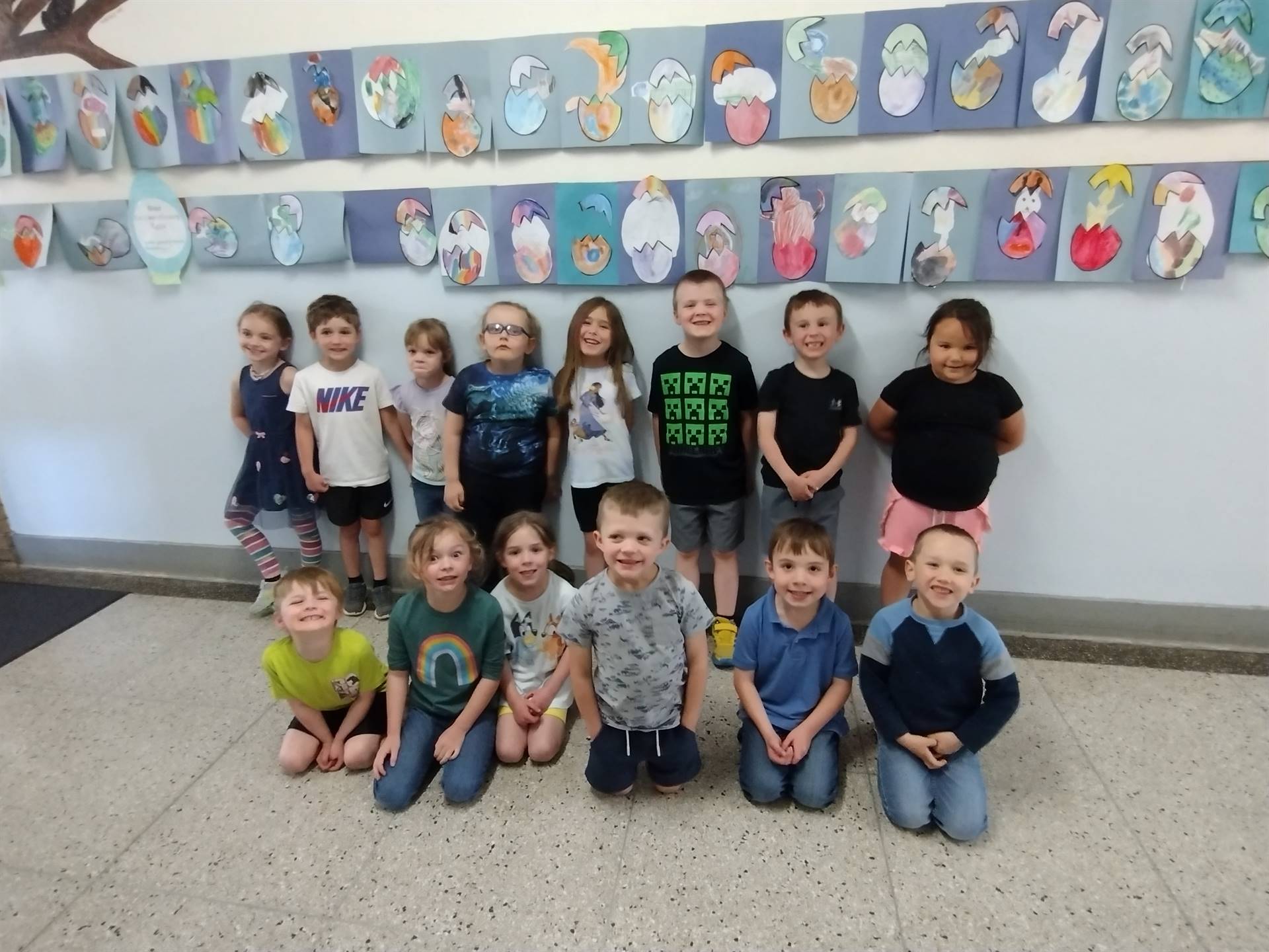 students standing in front of a background of art they created