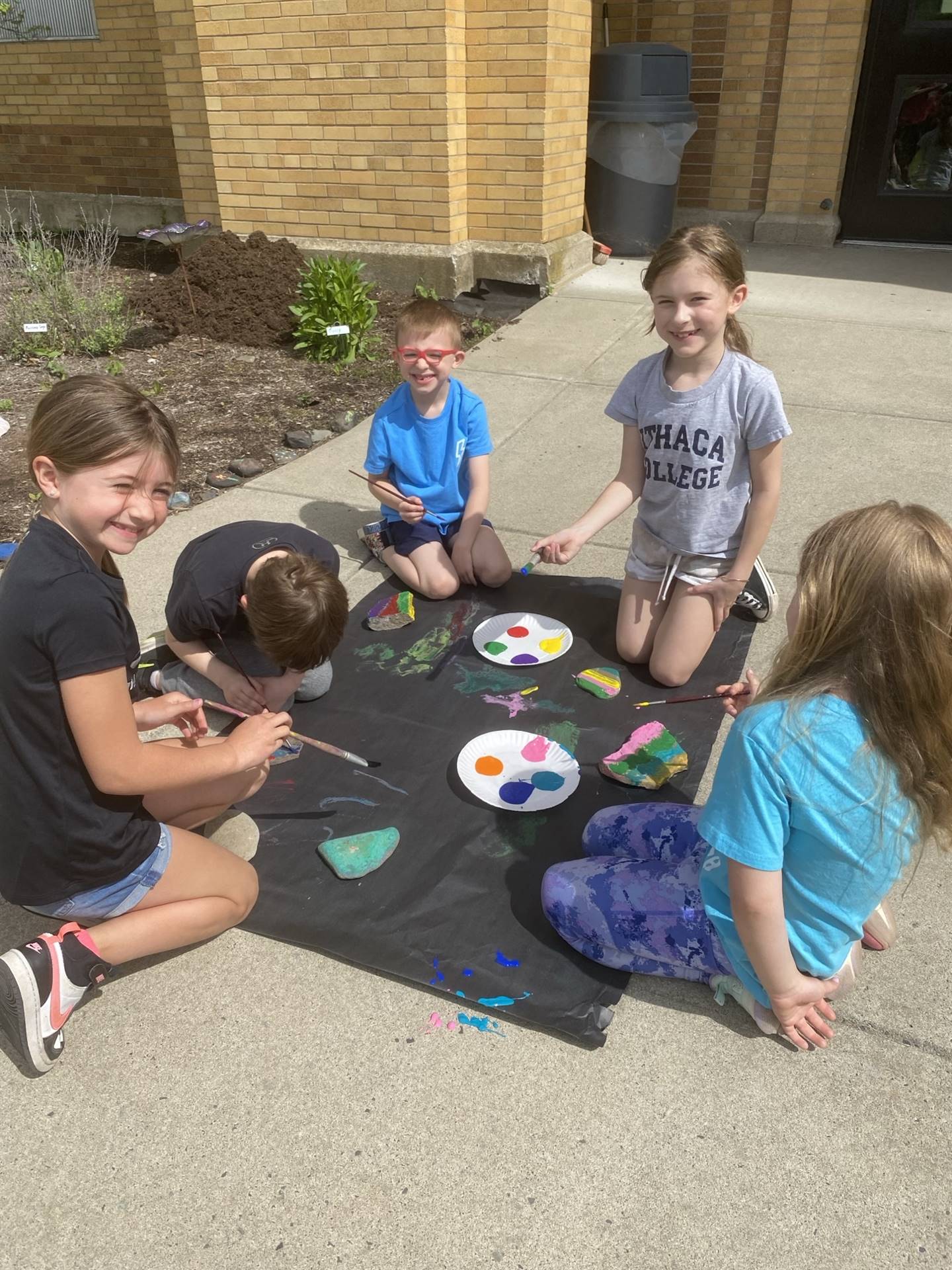 students on sidewalk painting rocks