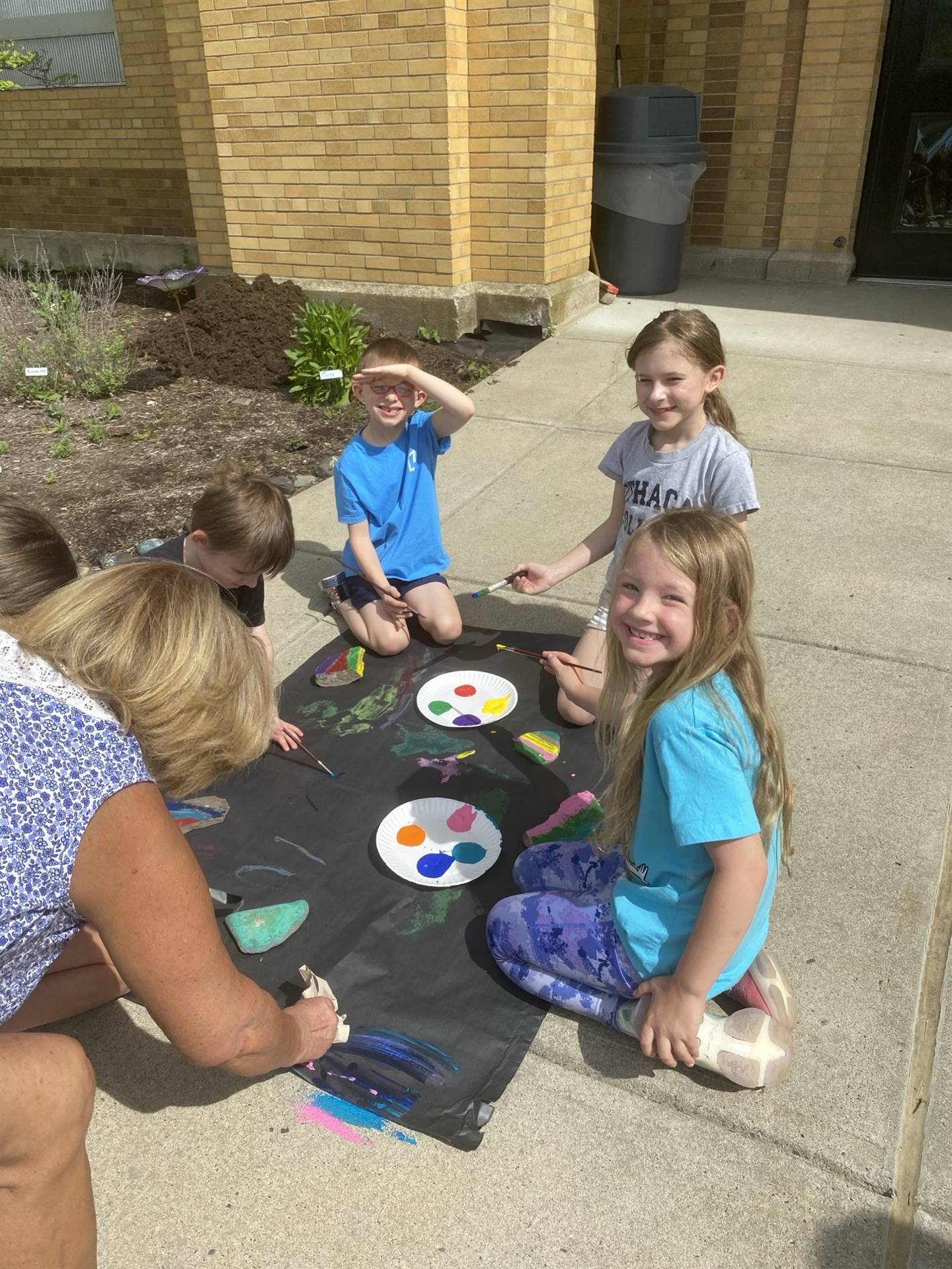 students on sidewalk painting rocks