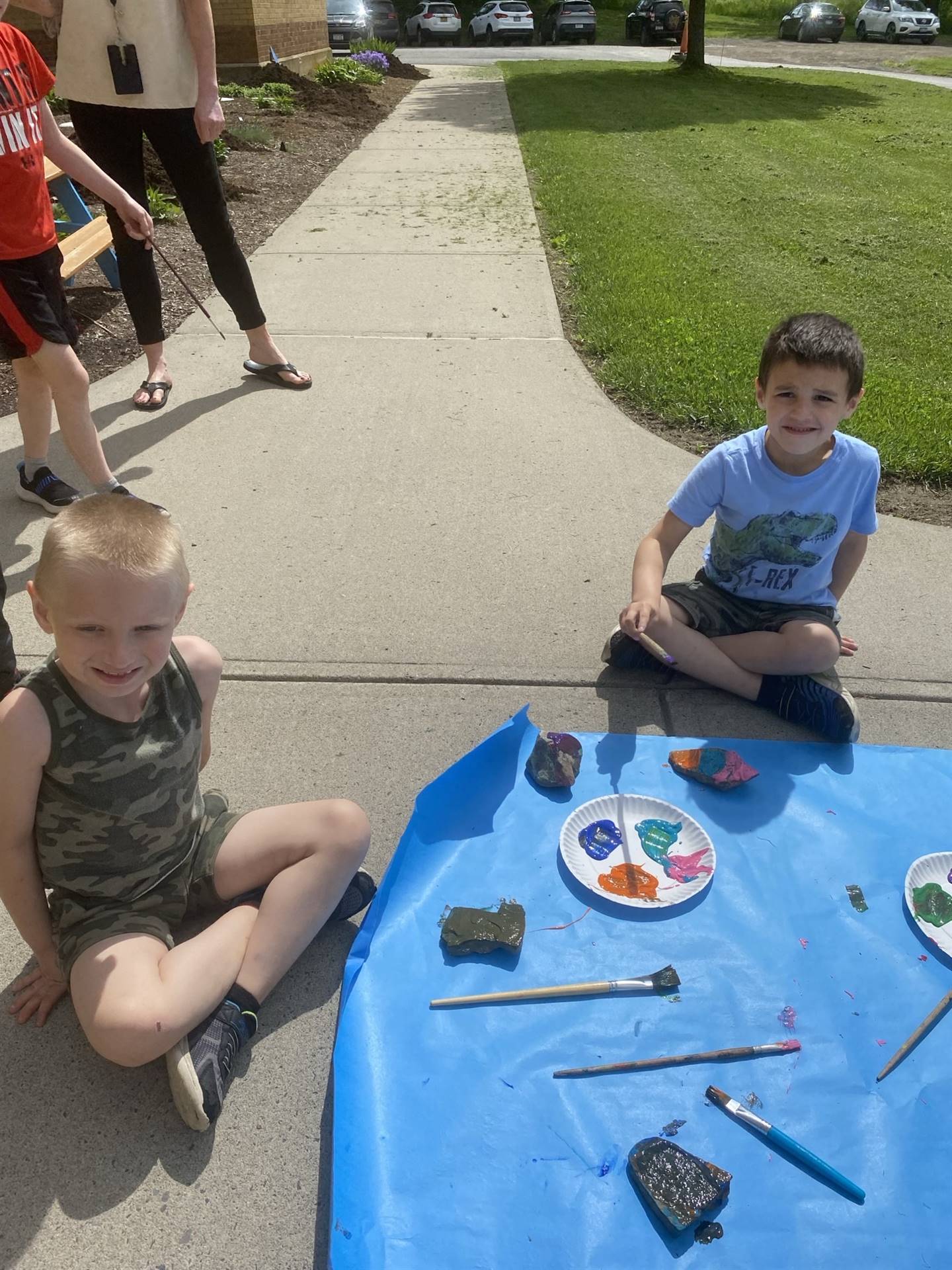 students on sidewalk painting rocks