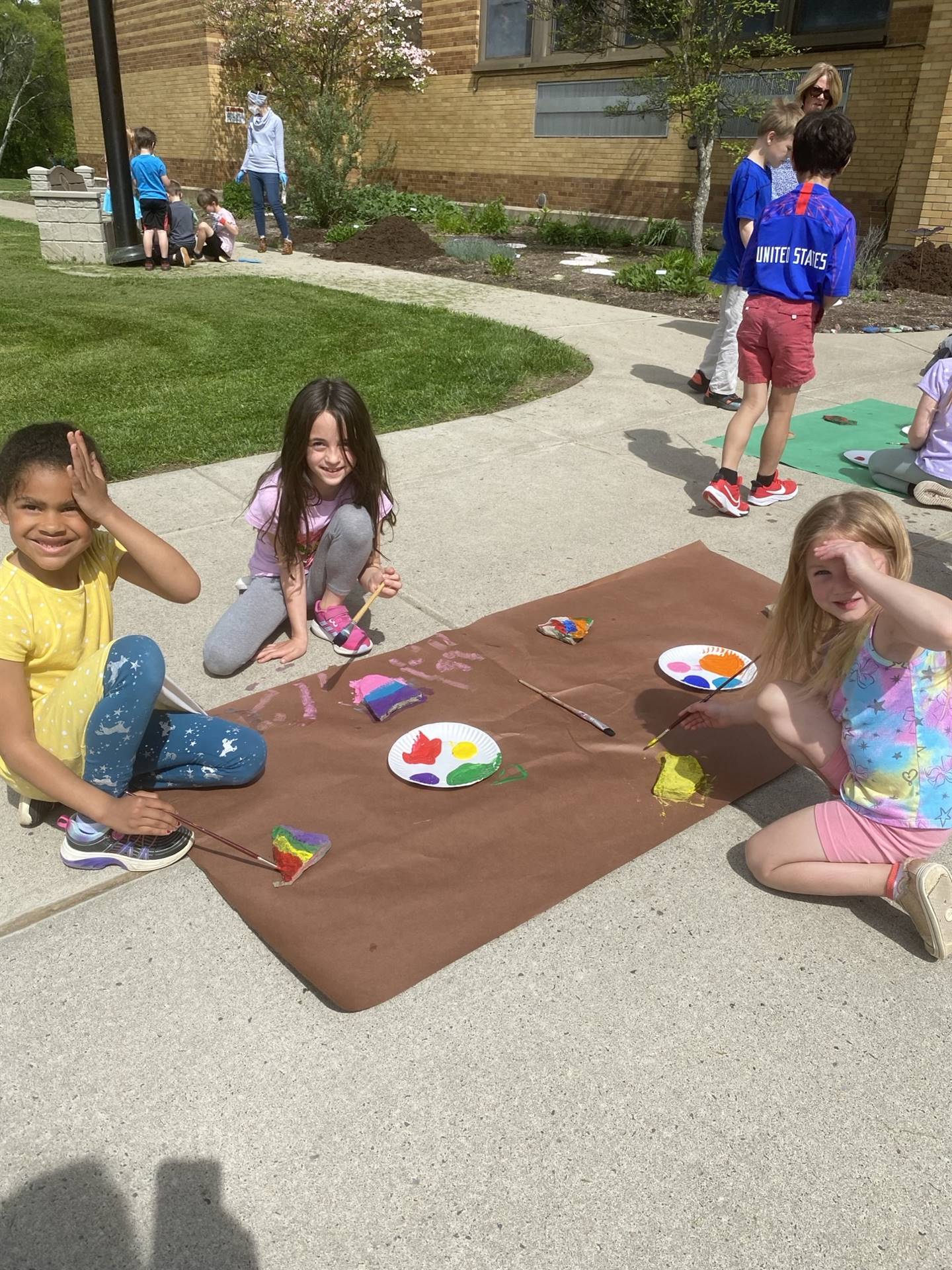 students on sidewalk painting rocks