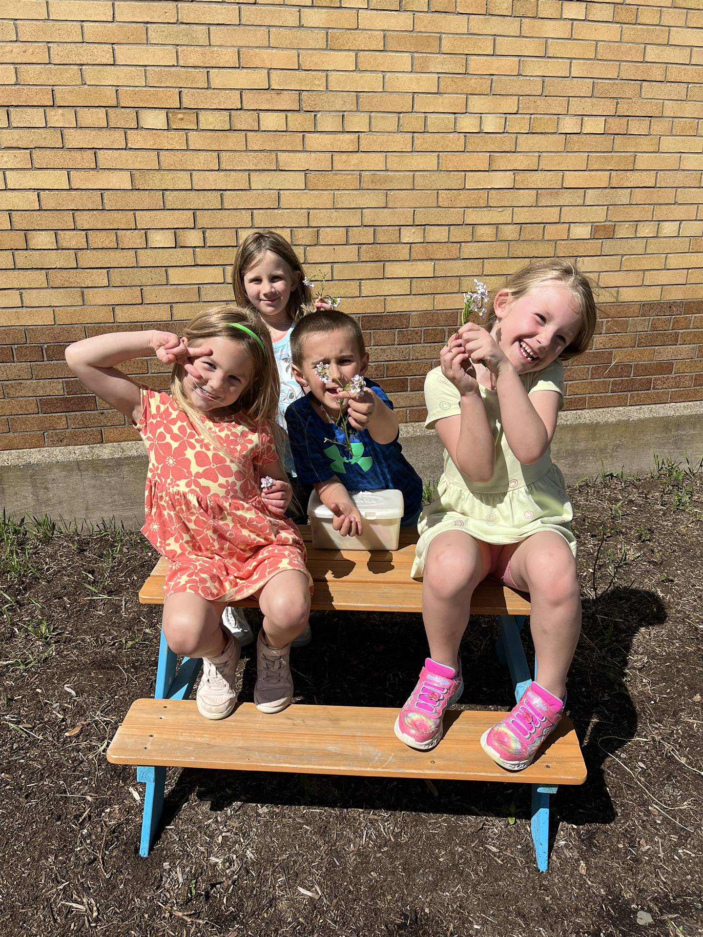 students outside sitting on a picnic bench with flowers.