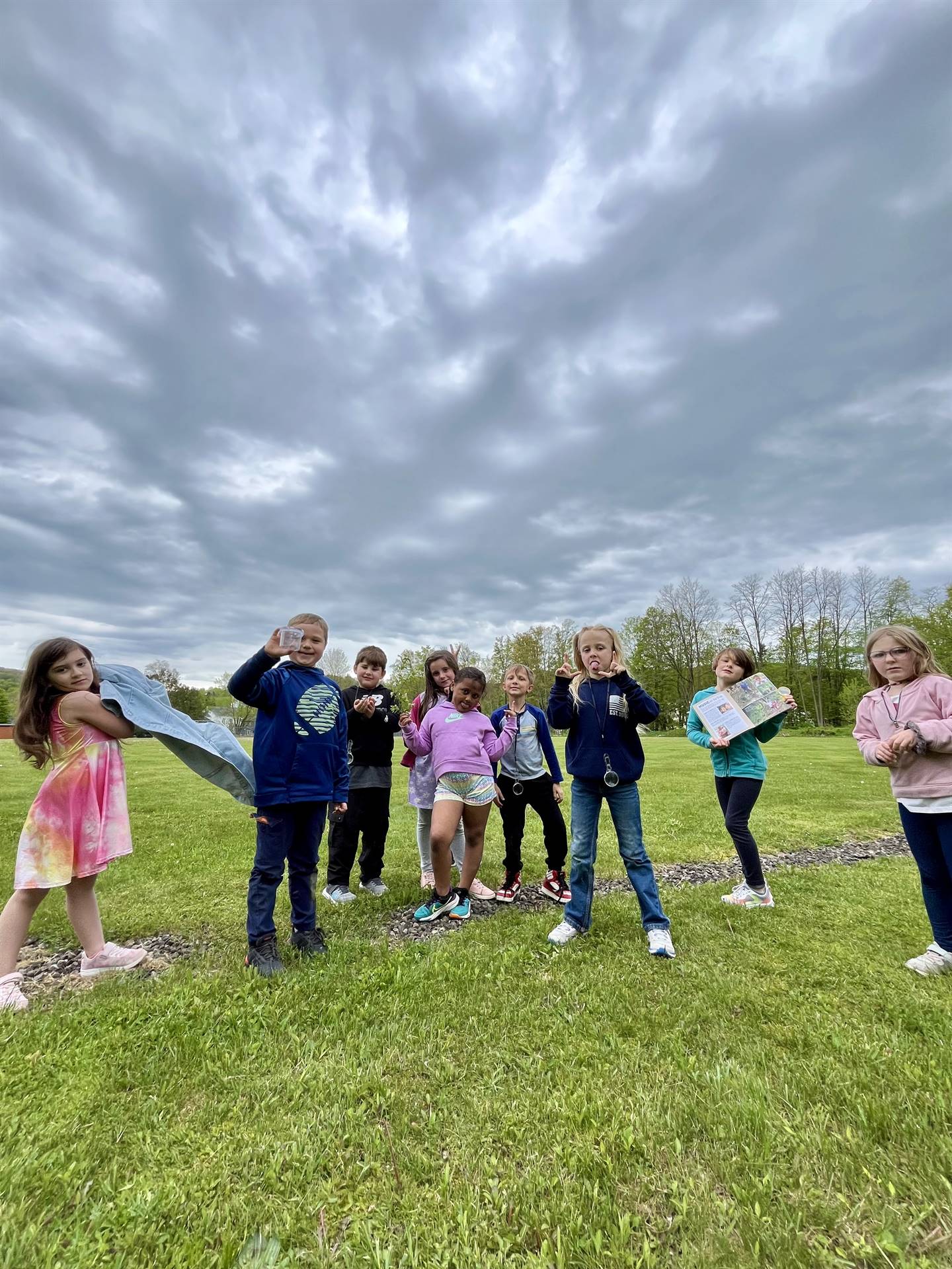 students outdoors holding up nature finds.