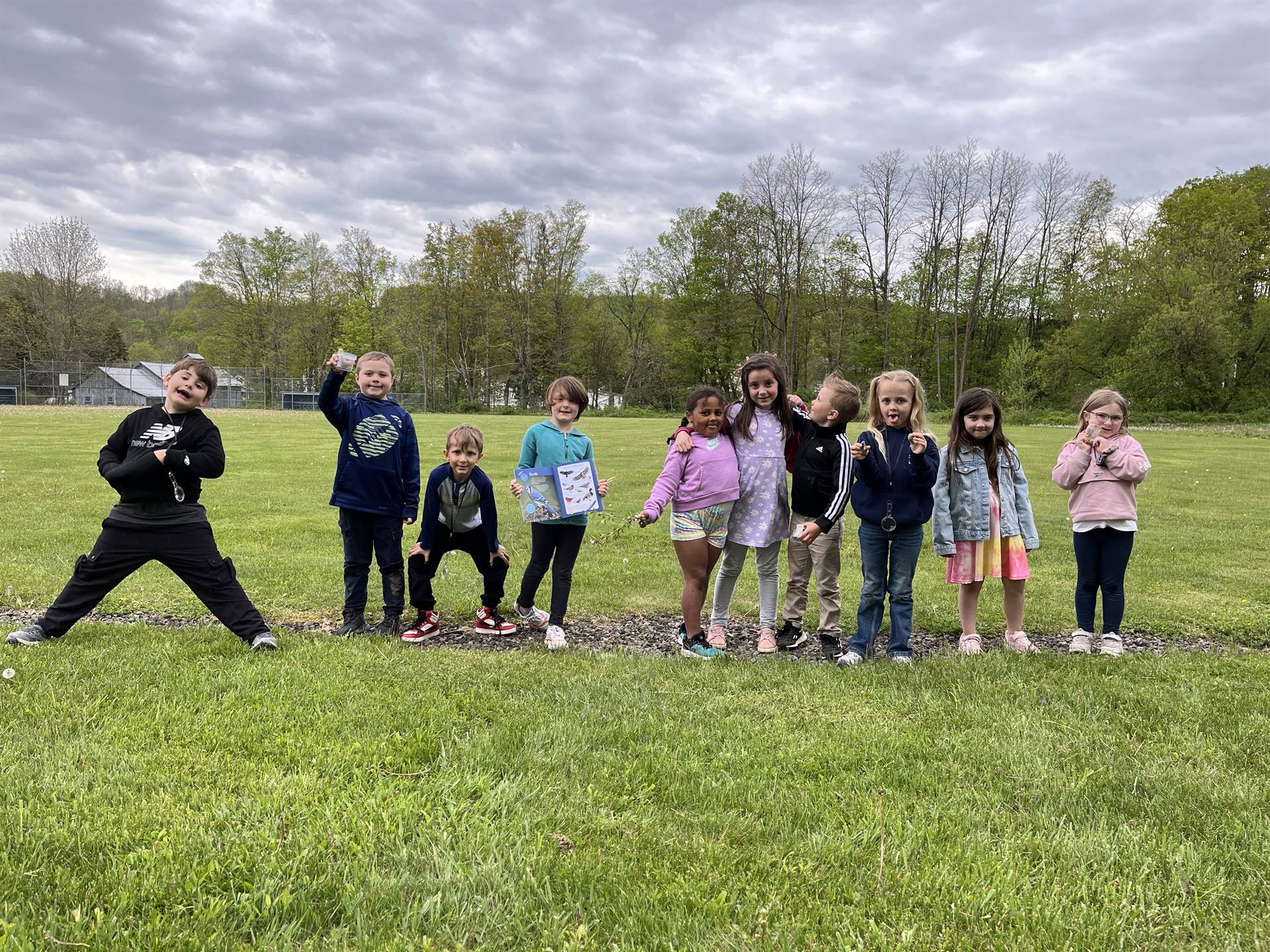 students outdoors holding up nature finds.