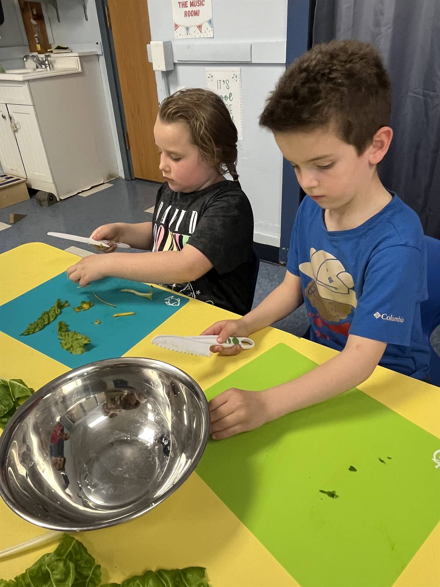 2 students cutting up swiss chard greens.