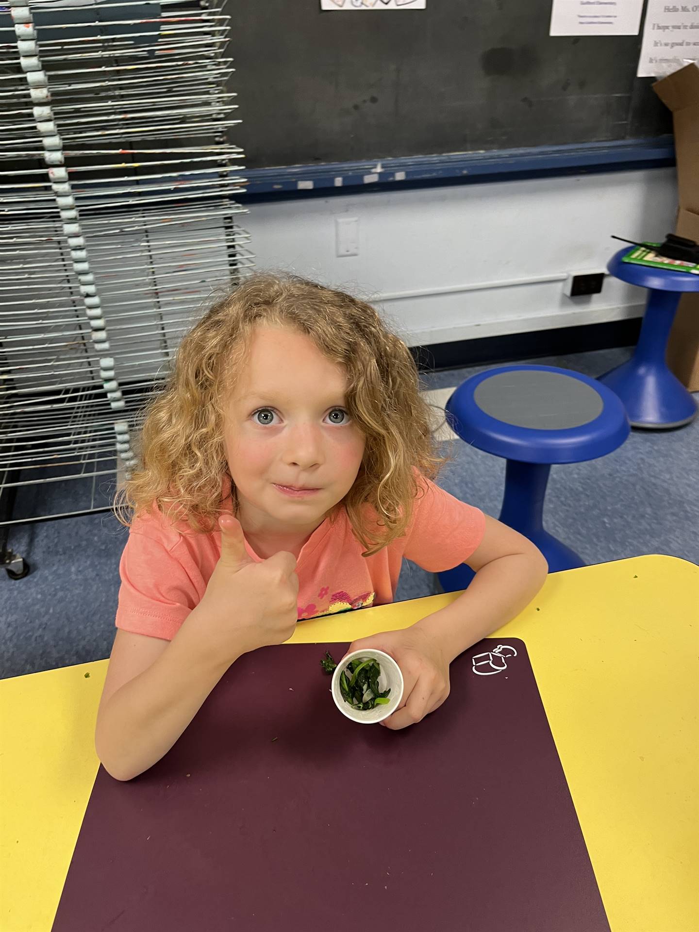 student holding cup of cooked greens.