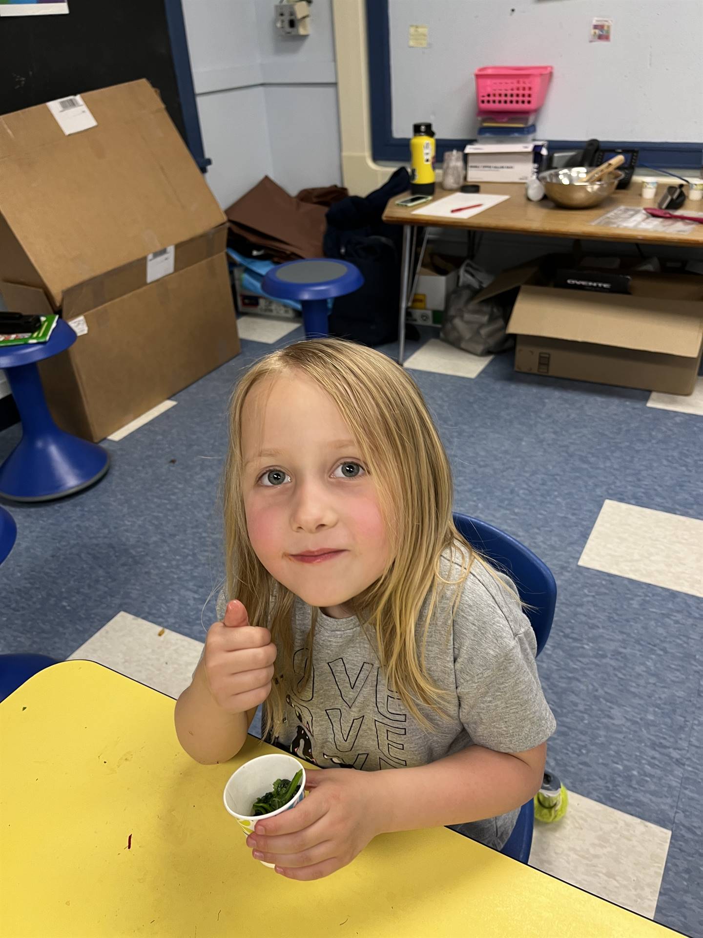 student holding cup of cooked greens.