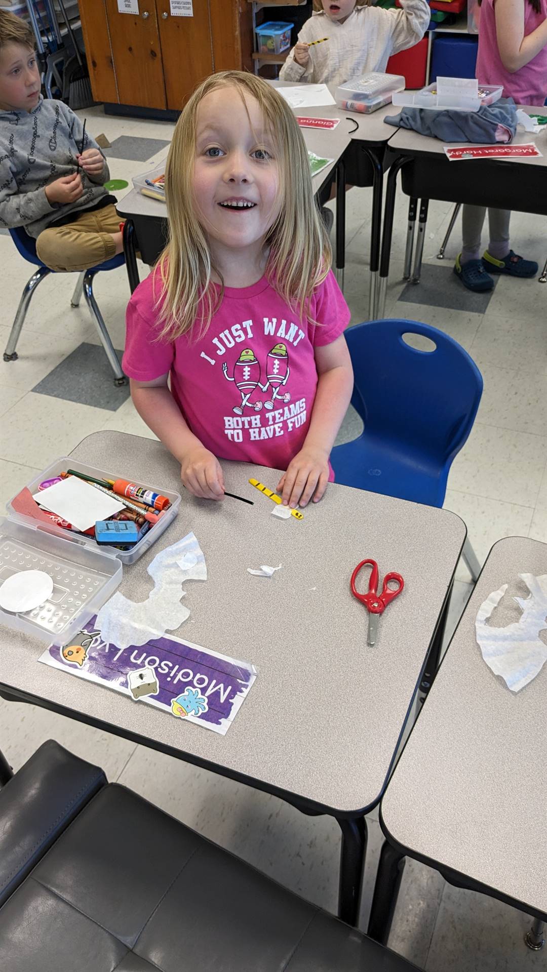 student standing at desk doing a craft.