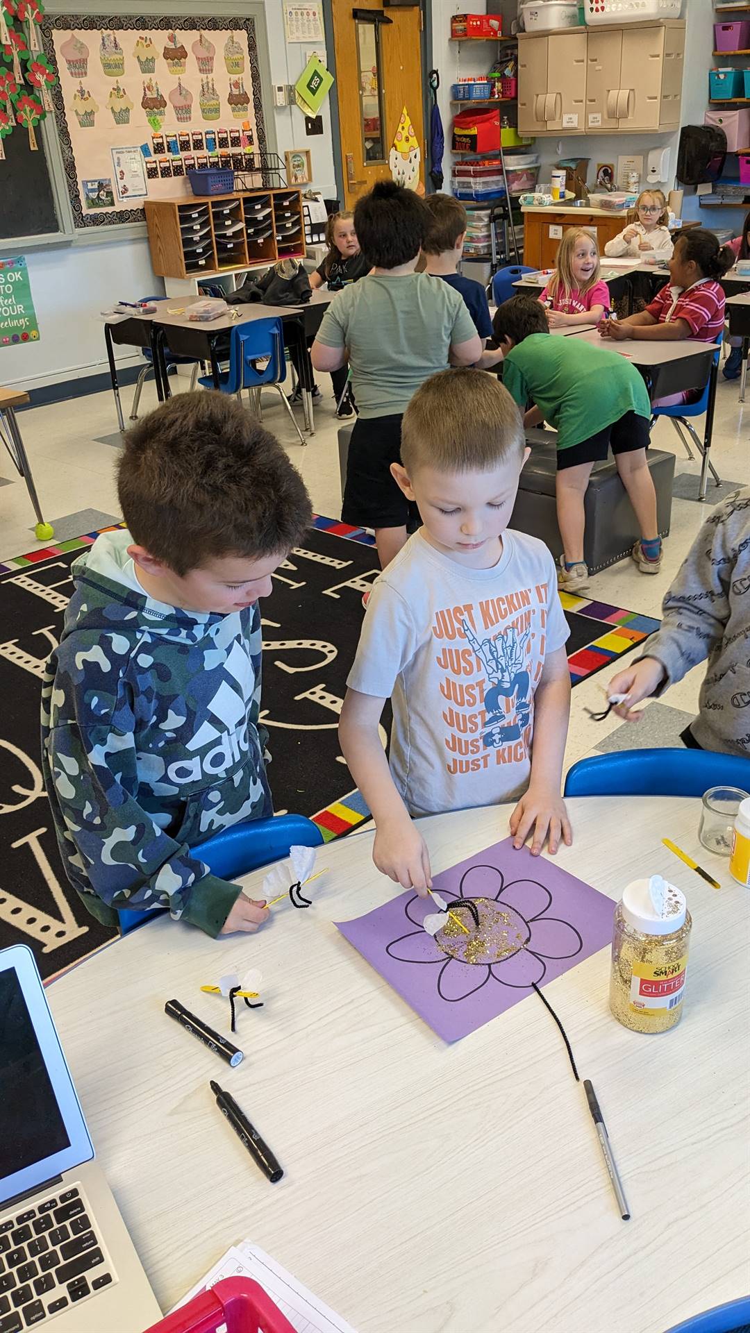 2 students coloring a paper flower together.