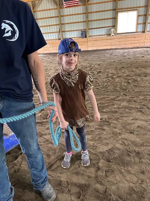 student helping to lead a horse by a rope.