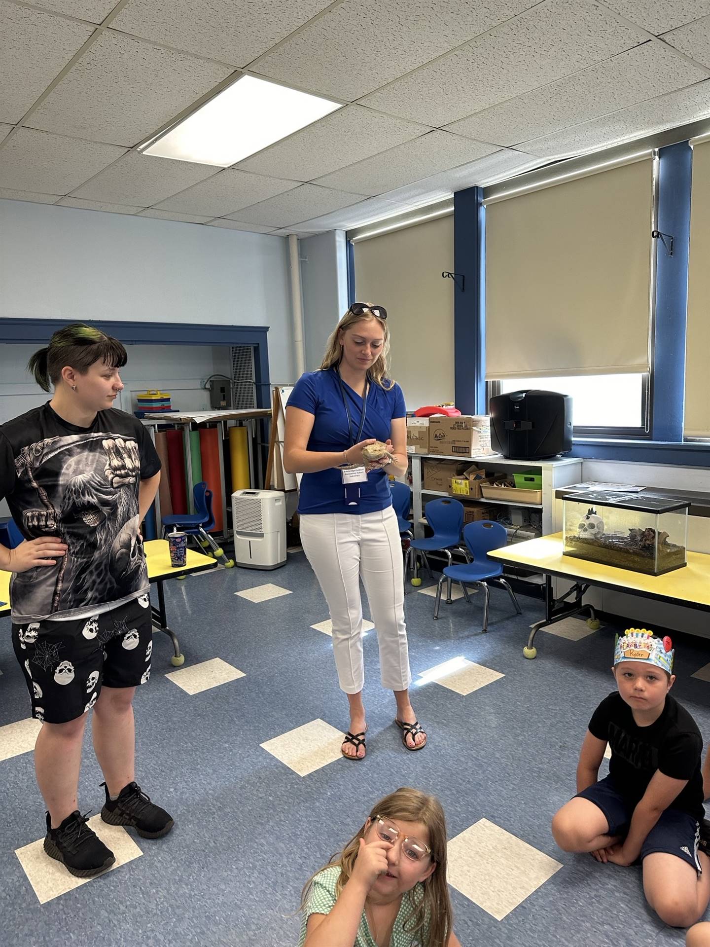 adult holding a reptile while students watch