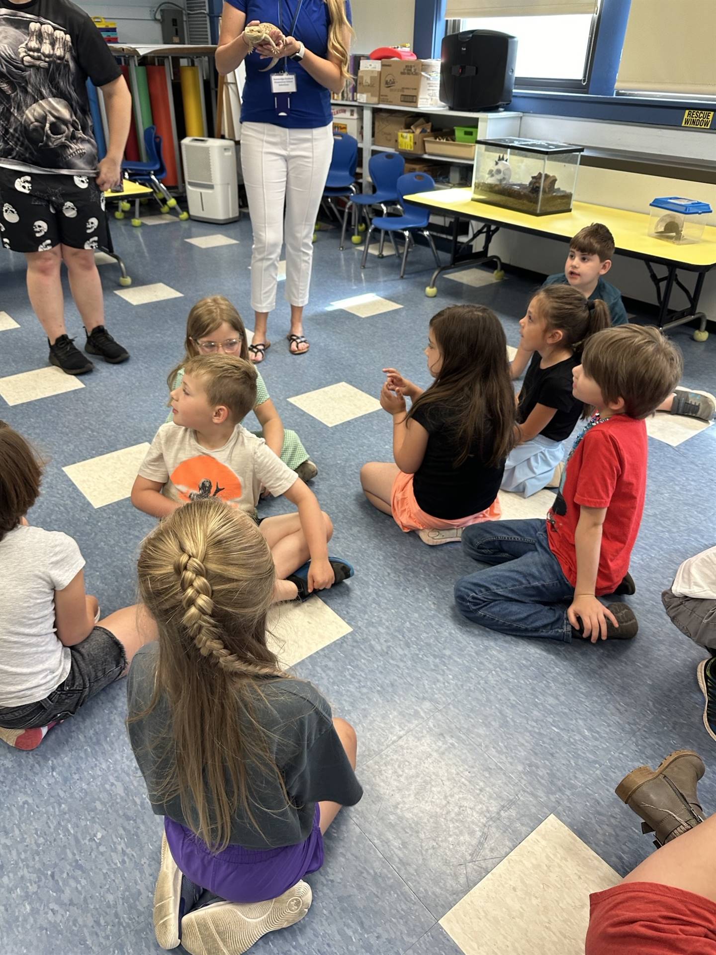 adult holding a reptile while students watch