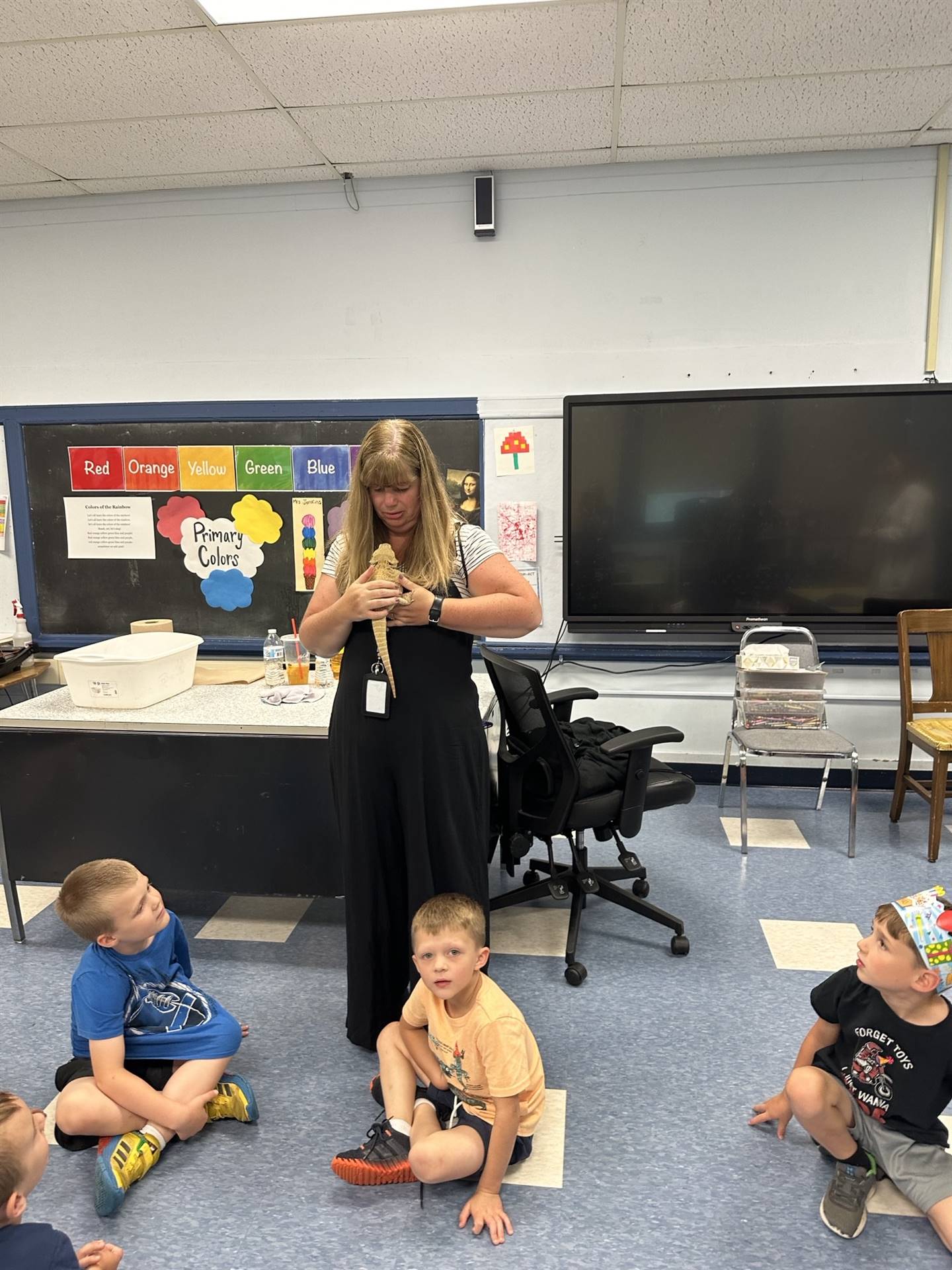 adult with a rainbow chameleon on her arm and kids watching