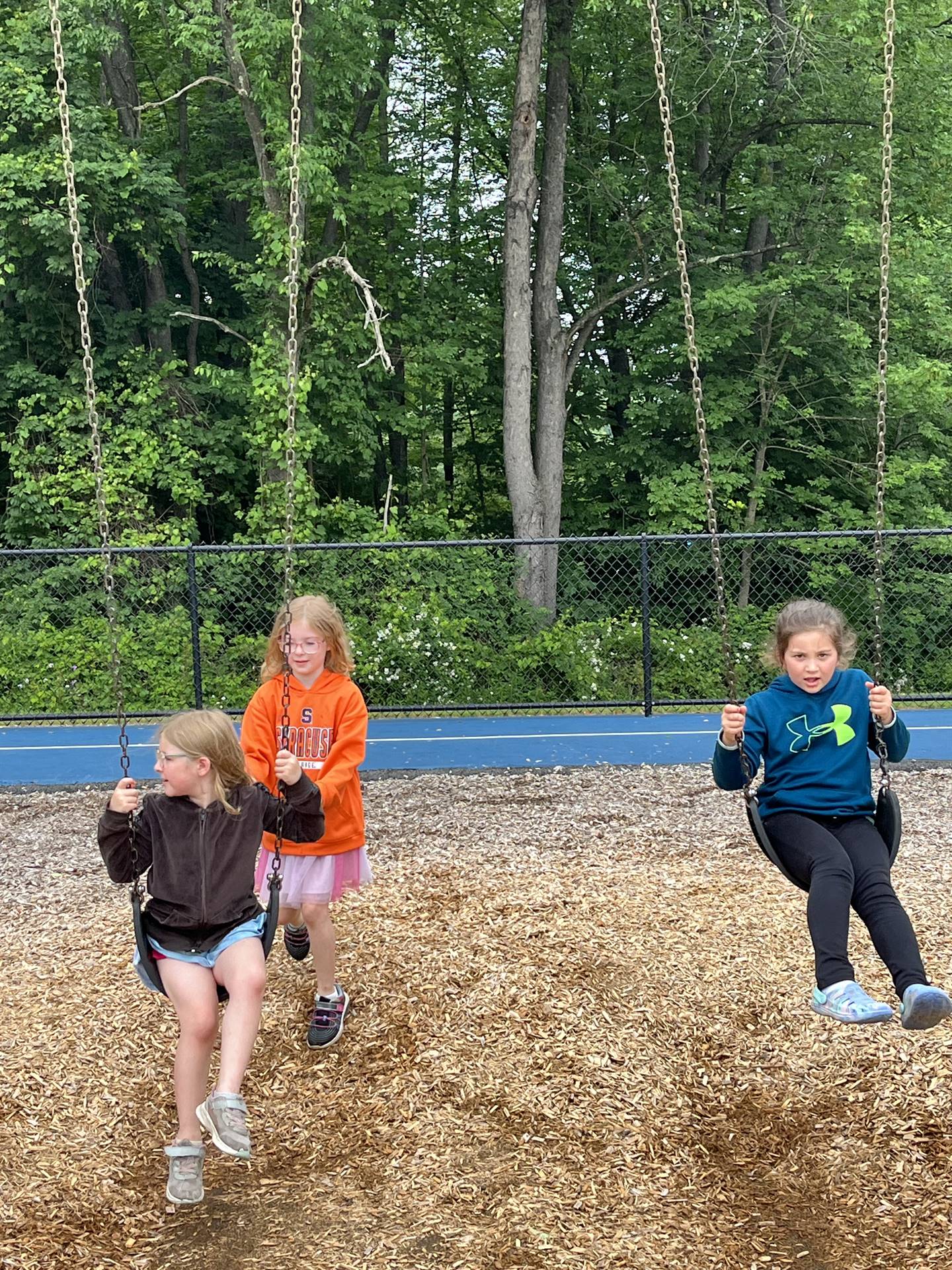 older student pushing younger student on swing